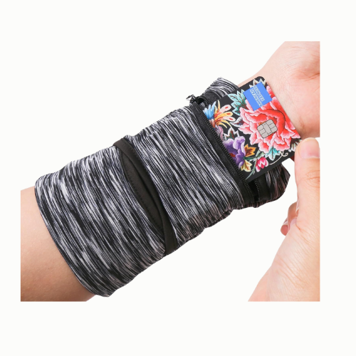 Een arm met een artruitin van zwarte en grijze stretchstof, waarin een hand een creditcard met bloemenprint vasthoudt.