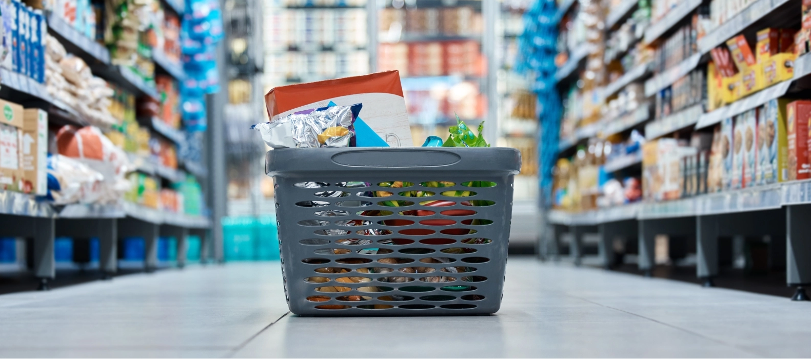 Indkøbskurv med vare på gulv i supermarked