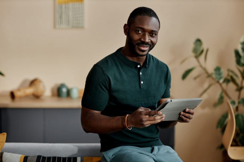 Man using a laptop while drinking coffee in a peaceful outdoor setting – symbolising the ease and flexibility of online ADHD and autism assessments.