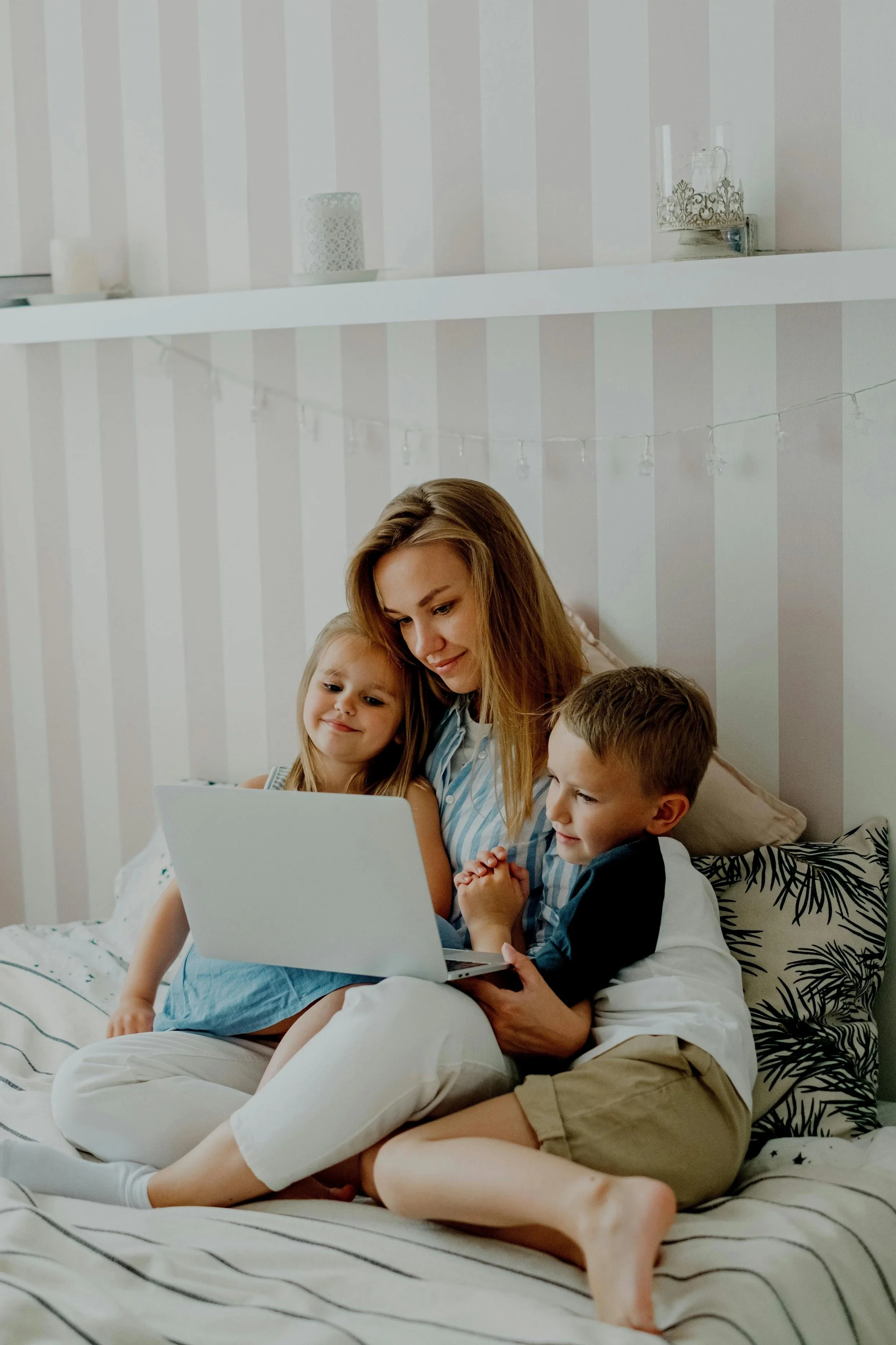 Smiling mother and two children using a laptop together on the sofa – reflecting timely, trusted ADHD and autism diagnosis for families.