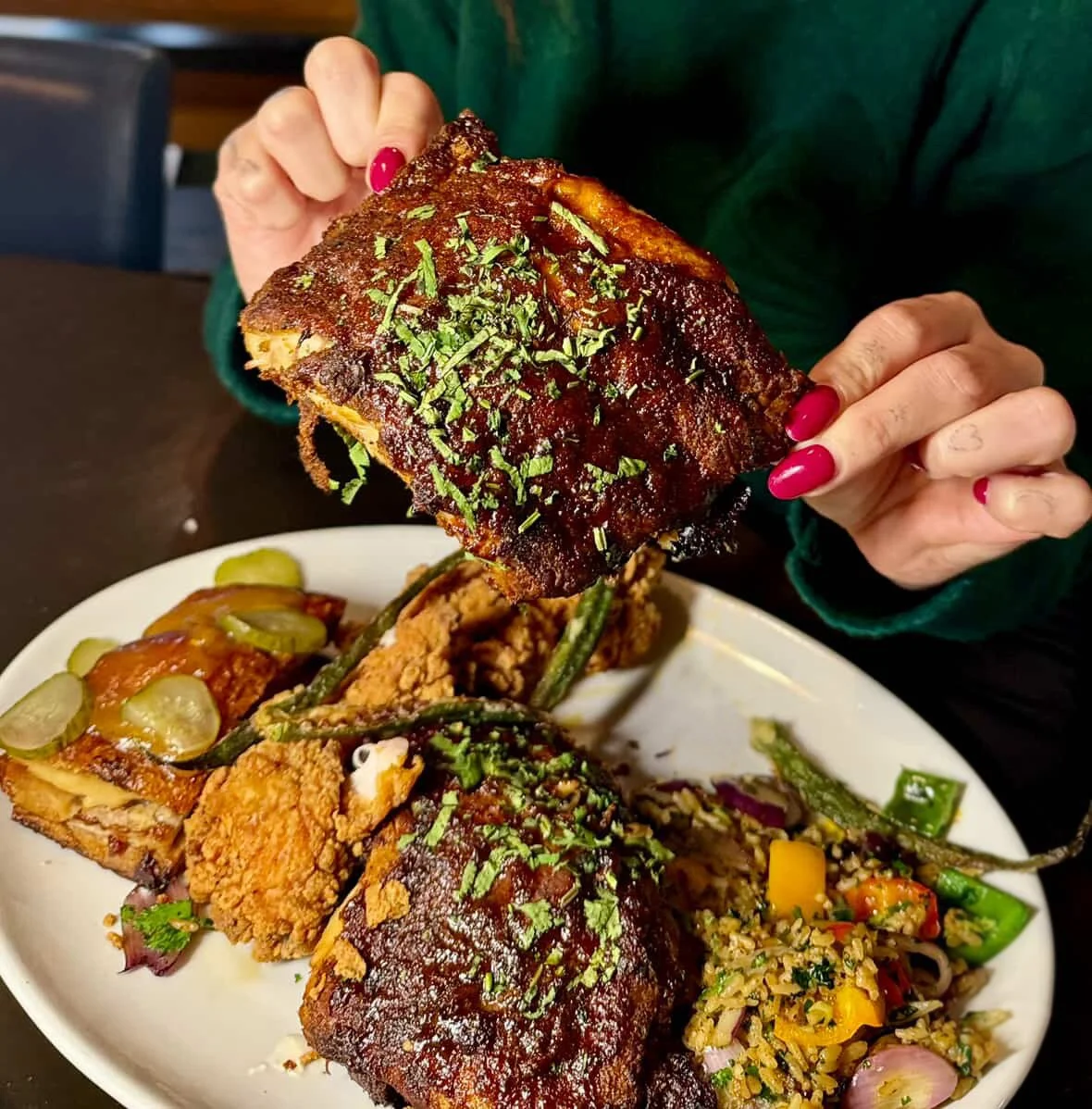 Woman with pink nails holding some juicy ribs over a Shakey's sharing platter