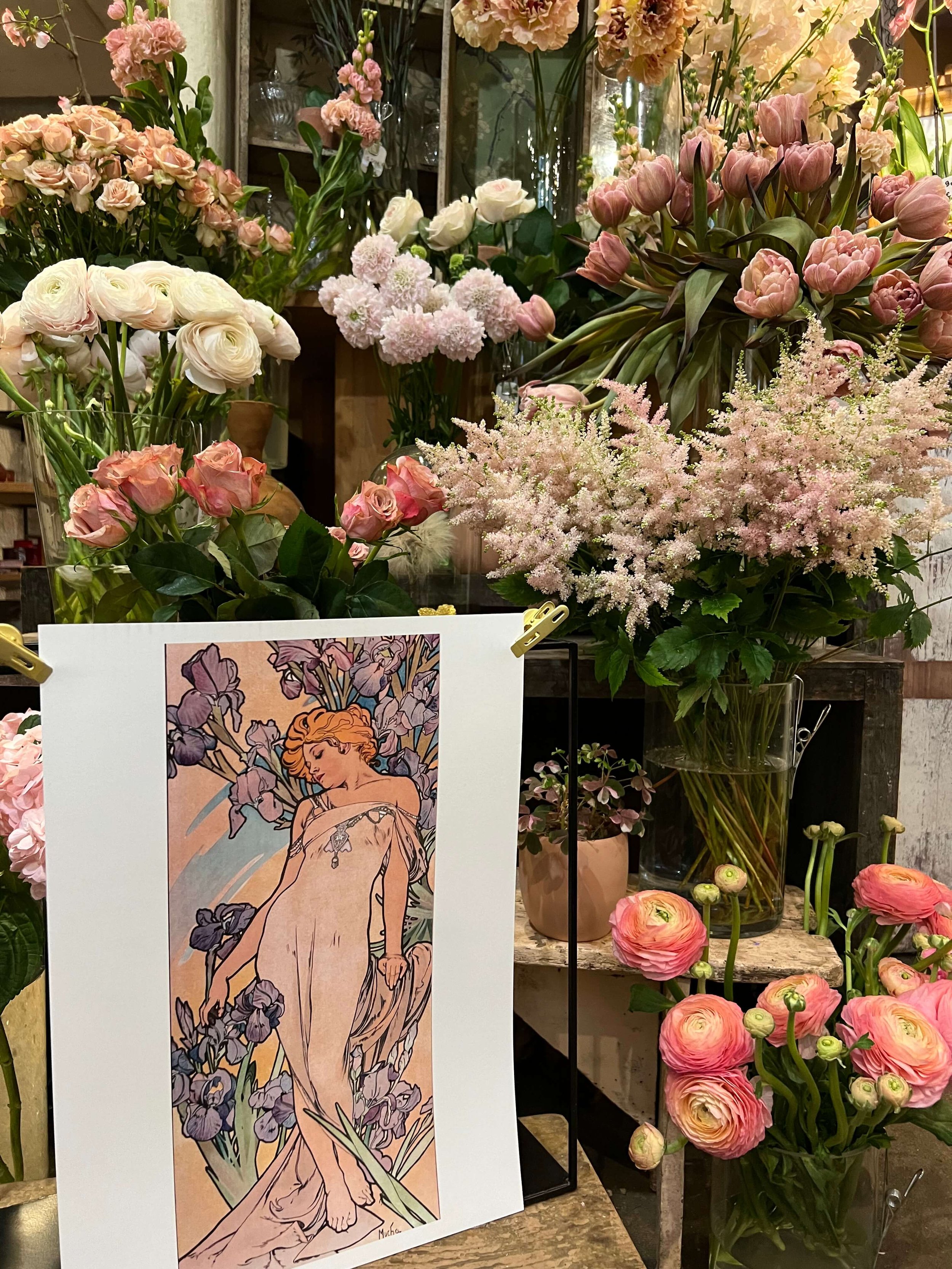 Présentation boutique avec fleurs fraîches, livres et affiche artistique. Une atmosphère poétique et inspirante.