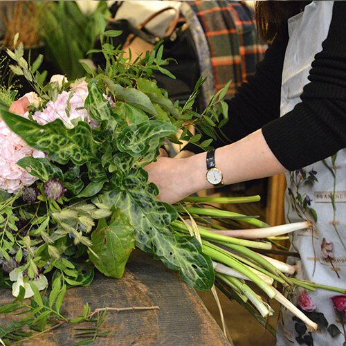 Détail d’un bouquet en construction, capturé en pleine gestuelle. Nature brute et savoir-faire.