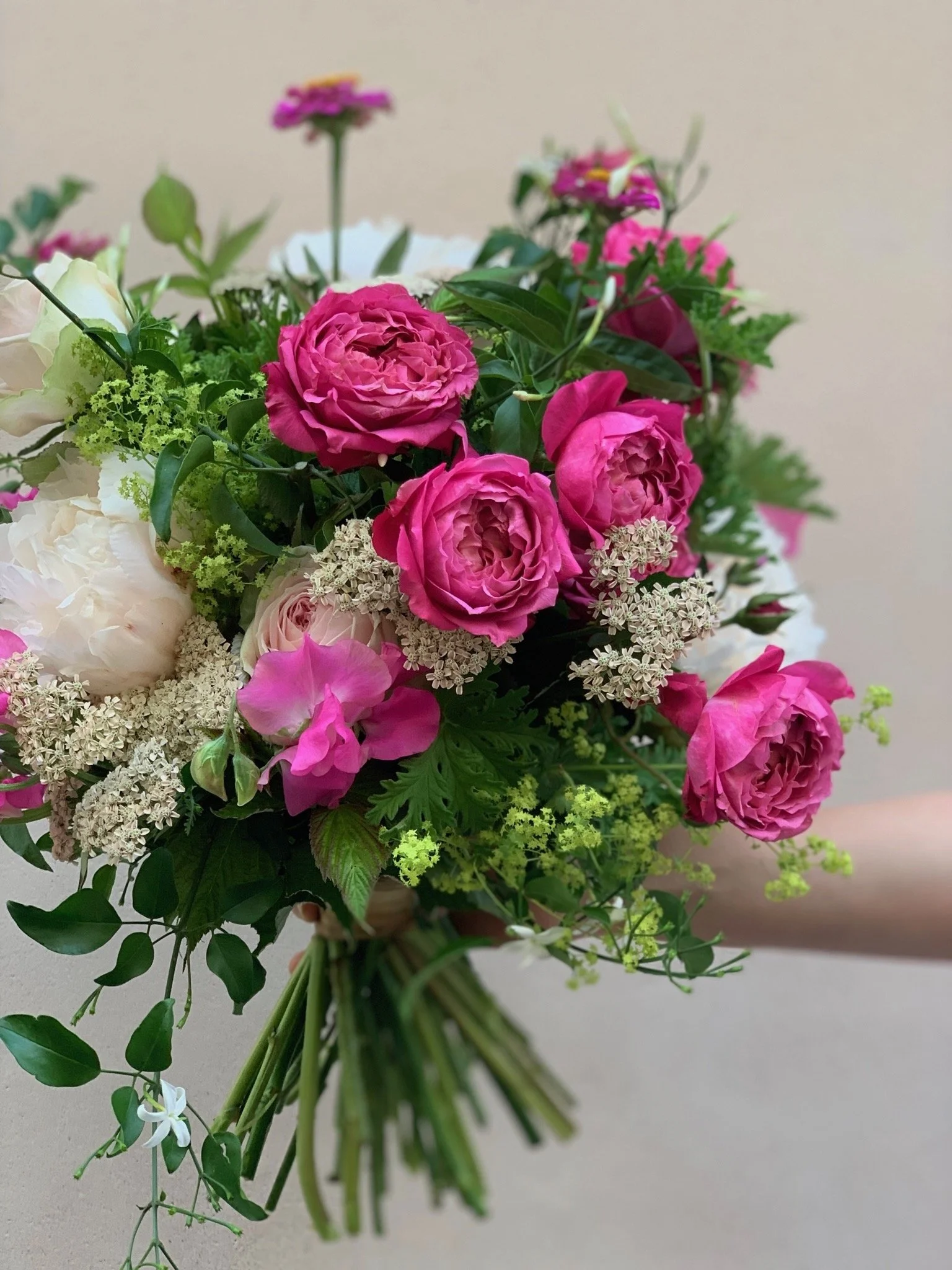 Bouquet de fleurs colorées avec des roses roses, des fleurs blanches, et d'autres petites fleurs vertes et roses.