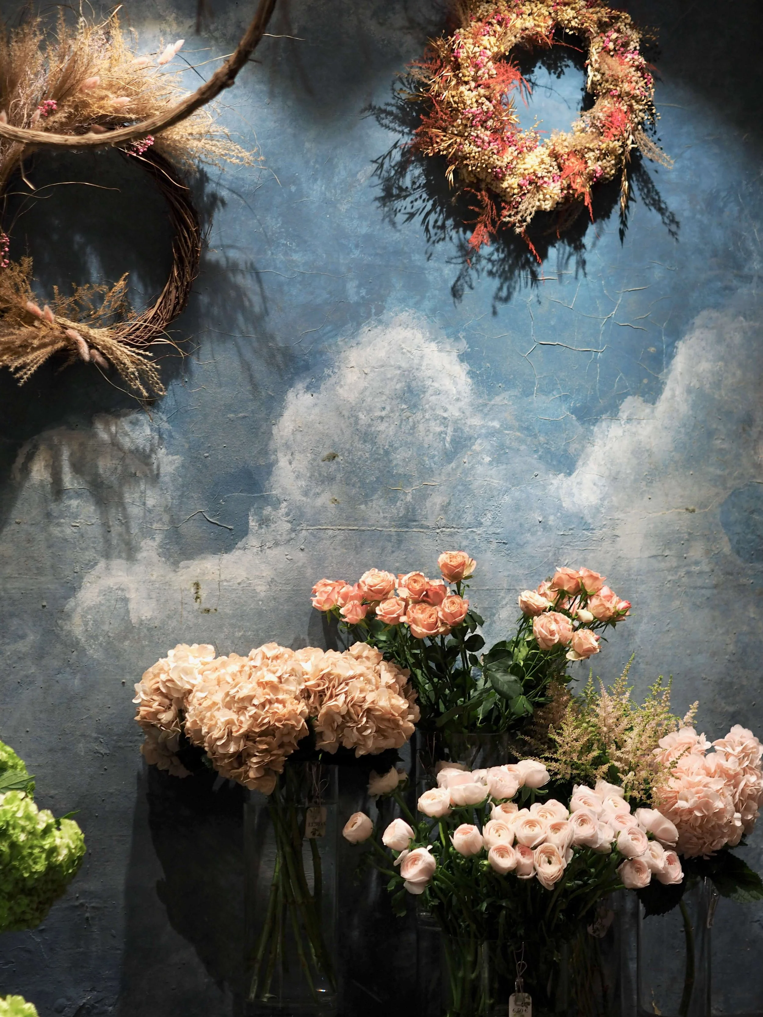 Murs bleu avec des fleurs séchées en guirlande et des bouquets de roses pâles dans des vases