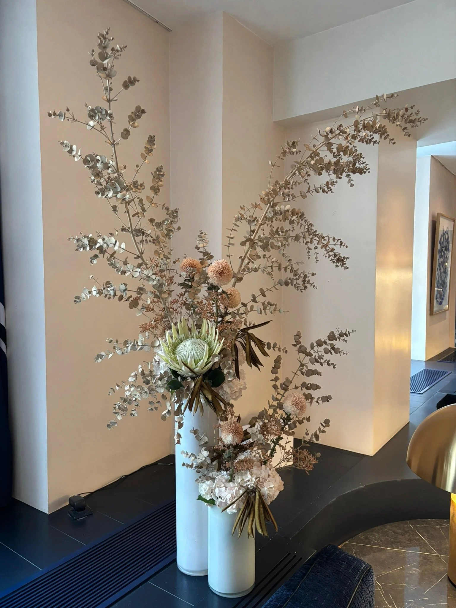 Composition florale avec des accessoires de décoration minimalistes dans un intérieur moderne, comprenant deux vases blancs avec des fleurs séchées dans un décor neutre et élégant.