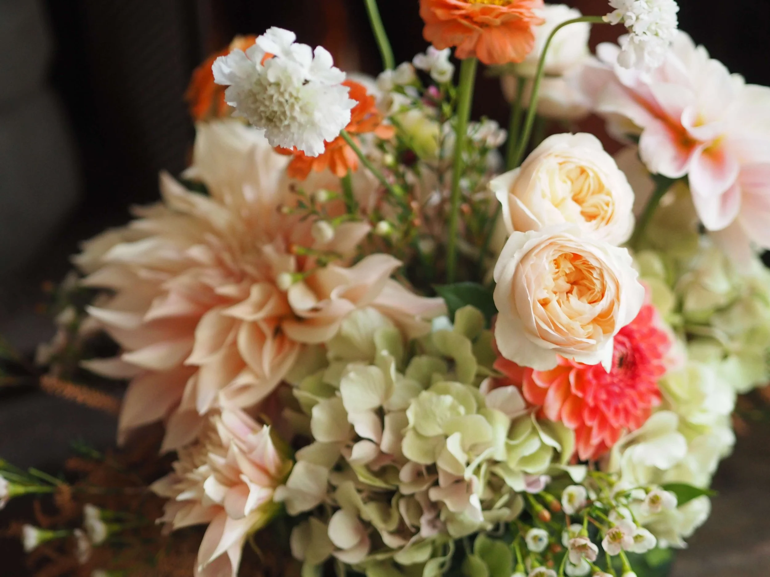 Un bouquet de fleurs composé de roses, d'hydrangéas, de dahlias et d'autres fleurs colorées.