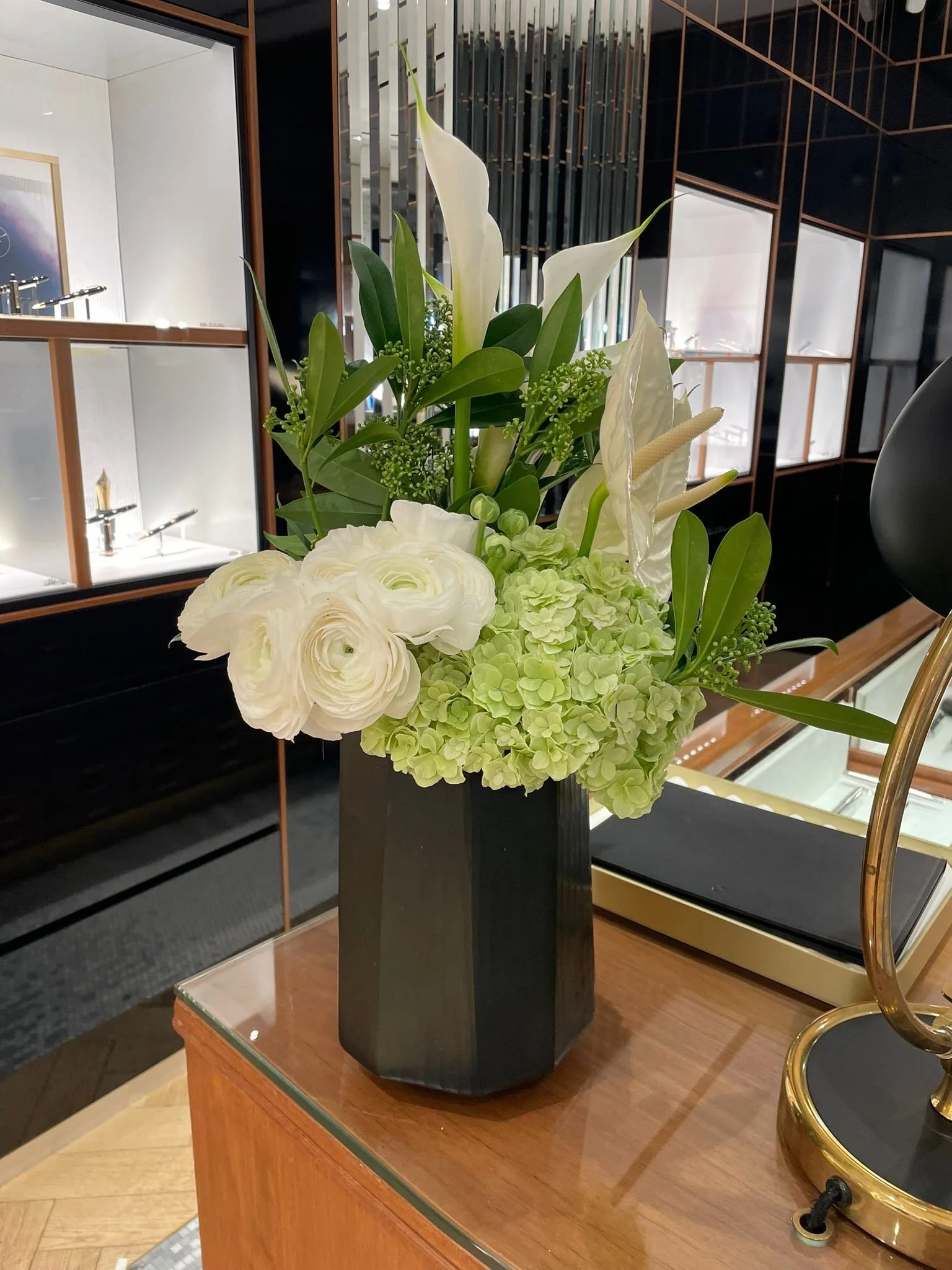 Un arrangement floral blanc et vert dans un vase noir dans un intérieur moderne.