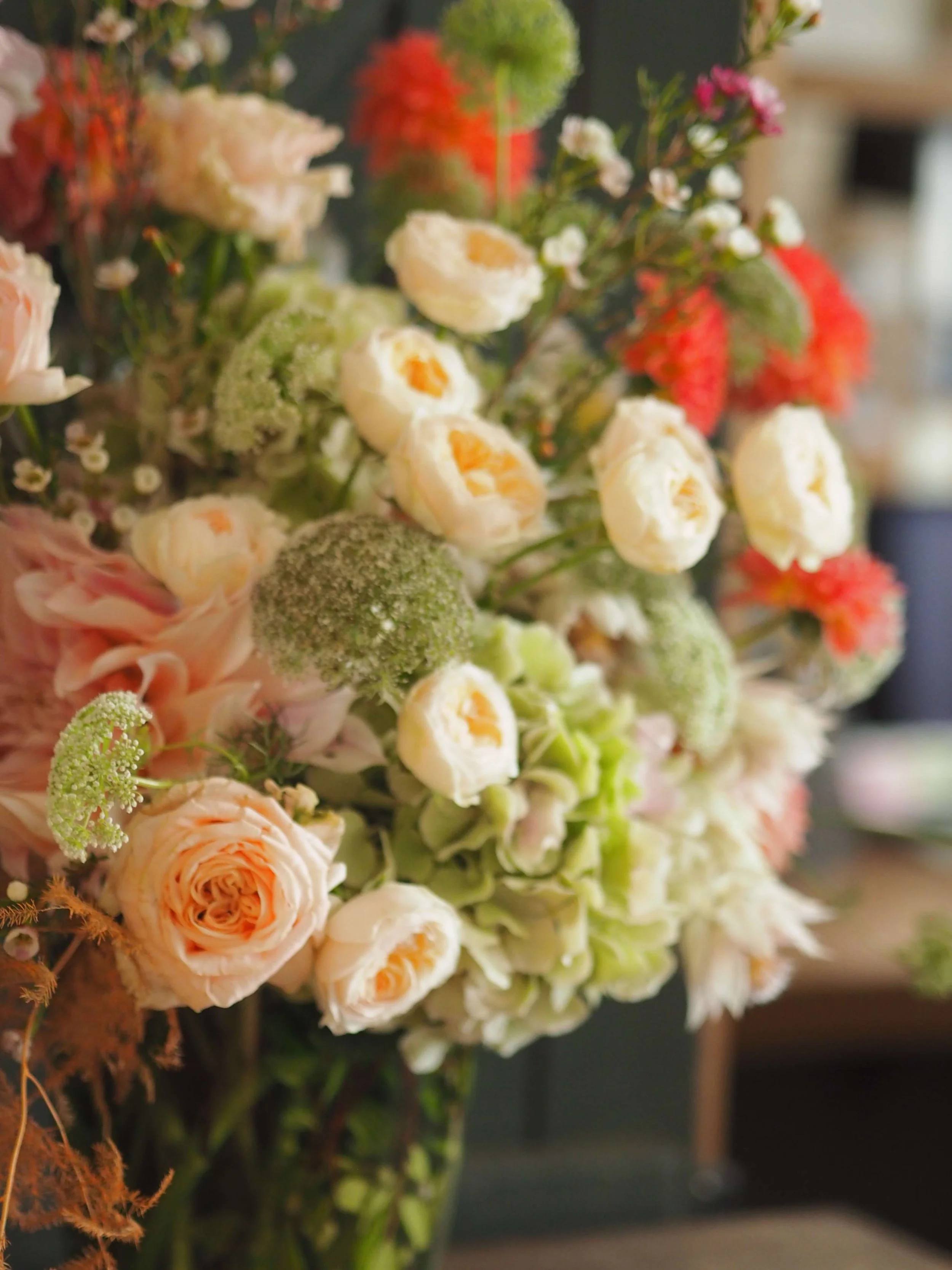 Un bouquet de fleurs composé de roses, de pivoines, et d'autres fleurs colorées fraîches dans un vase.