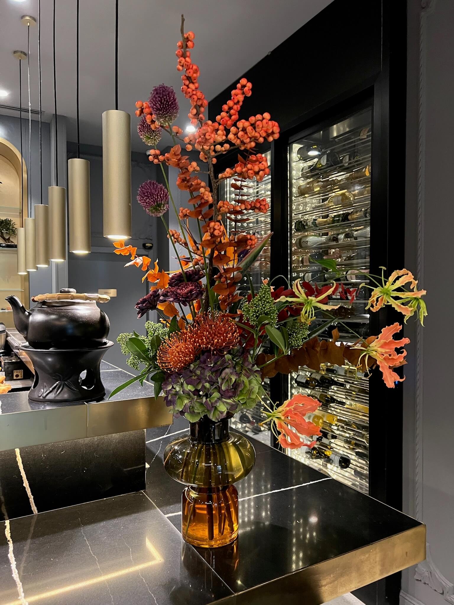 Un bouquet de fleurs colorées dans un vase en verre marron placé sur un comptoir noir.