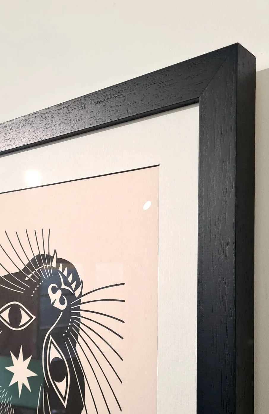 Close-up of a hand-crafted black wooden picture frame with white mount, showing a graphic print, made at Image Framers, Sligo