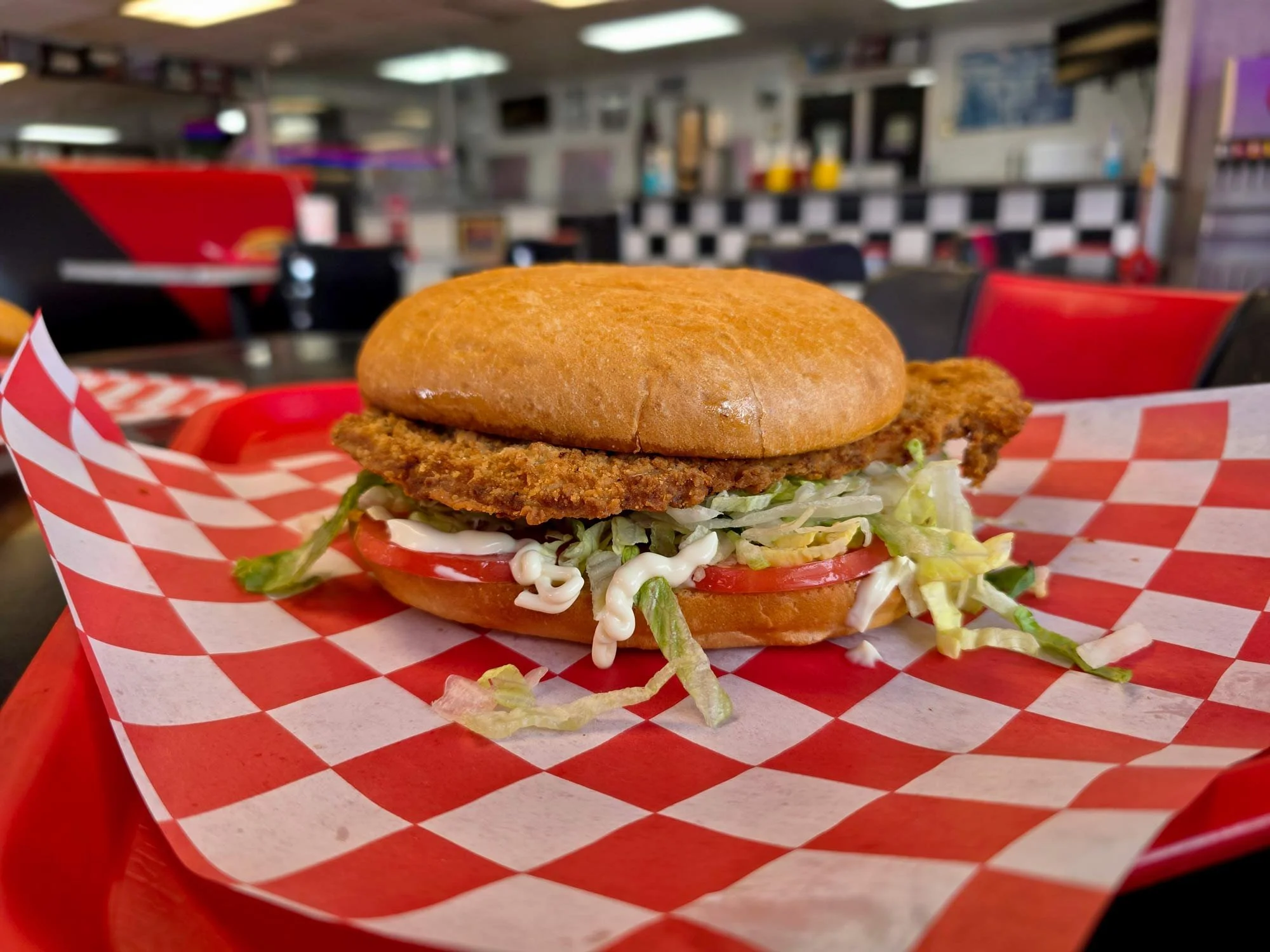 Iowa Pork Loin with breaded pork loin in a giant burger bun, with lettuce, tomato and mayo.
