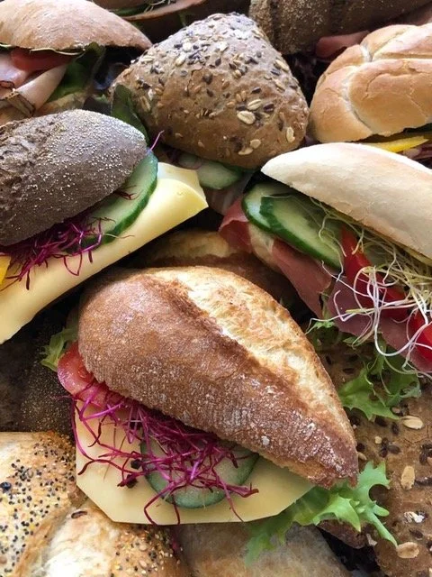 Assortiment van verschillende broodjes met ham, kaas, komkommer, sla en spruitjes.