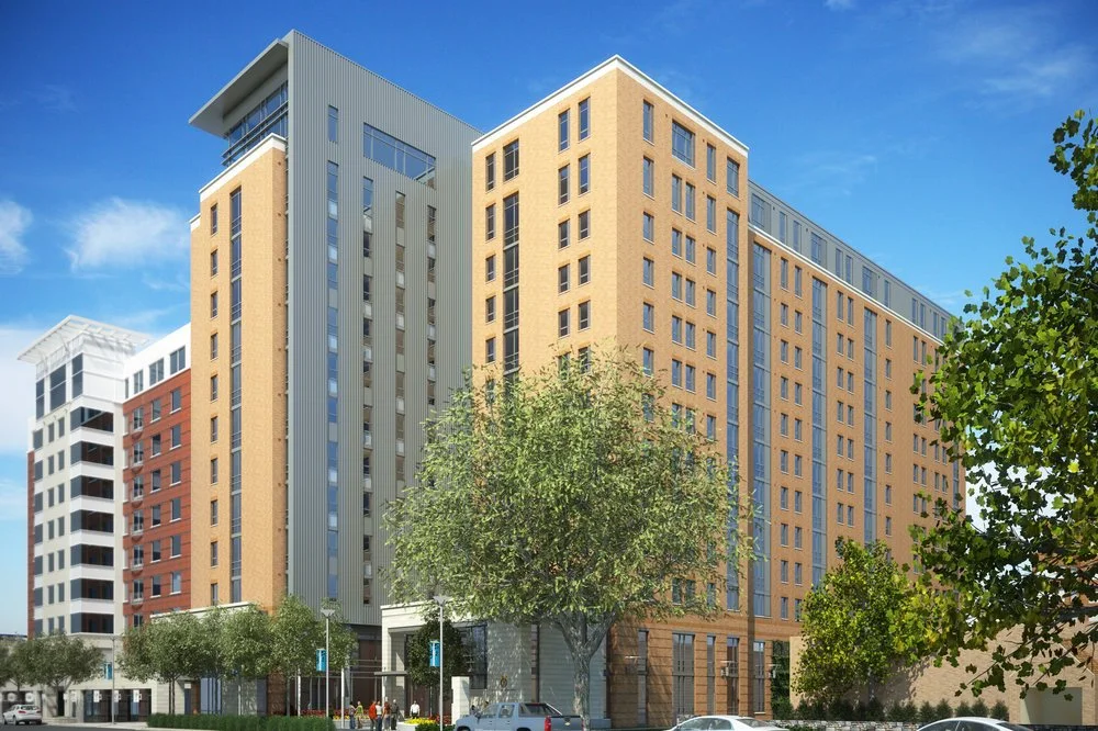 varsity in ann arbor michigan, housing reviews, tall apartment building in central campus. Modern multi-story apartment buildings with trees and cars in front, against a bright blue sky.