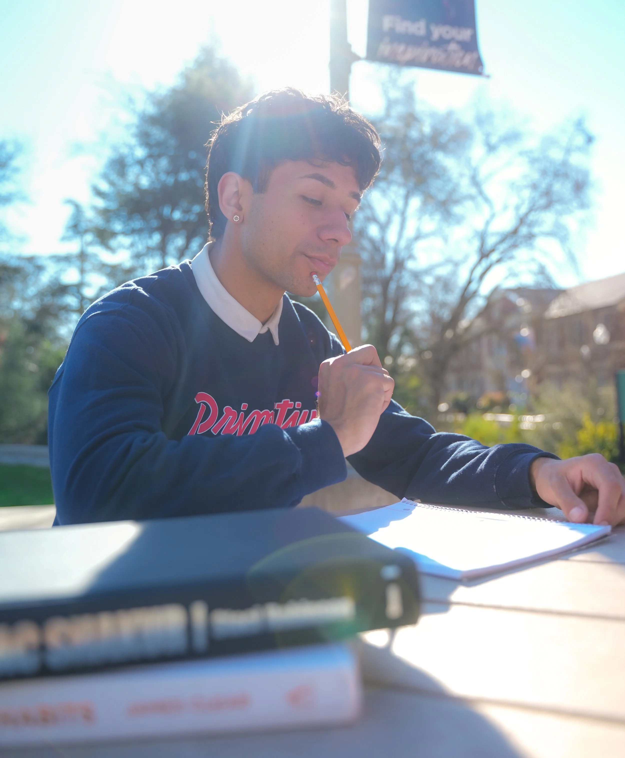 Person outdoors writing in notebook with sunlight shining