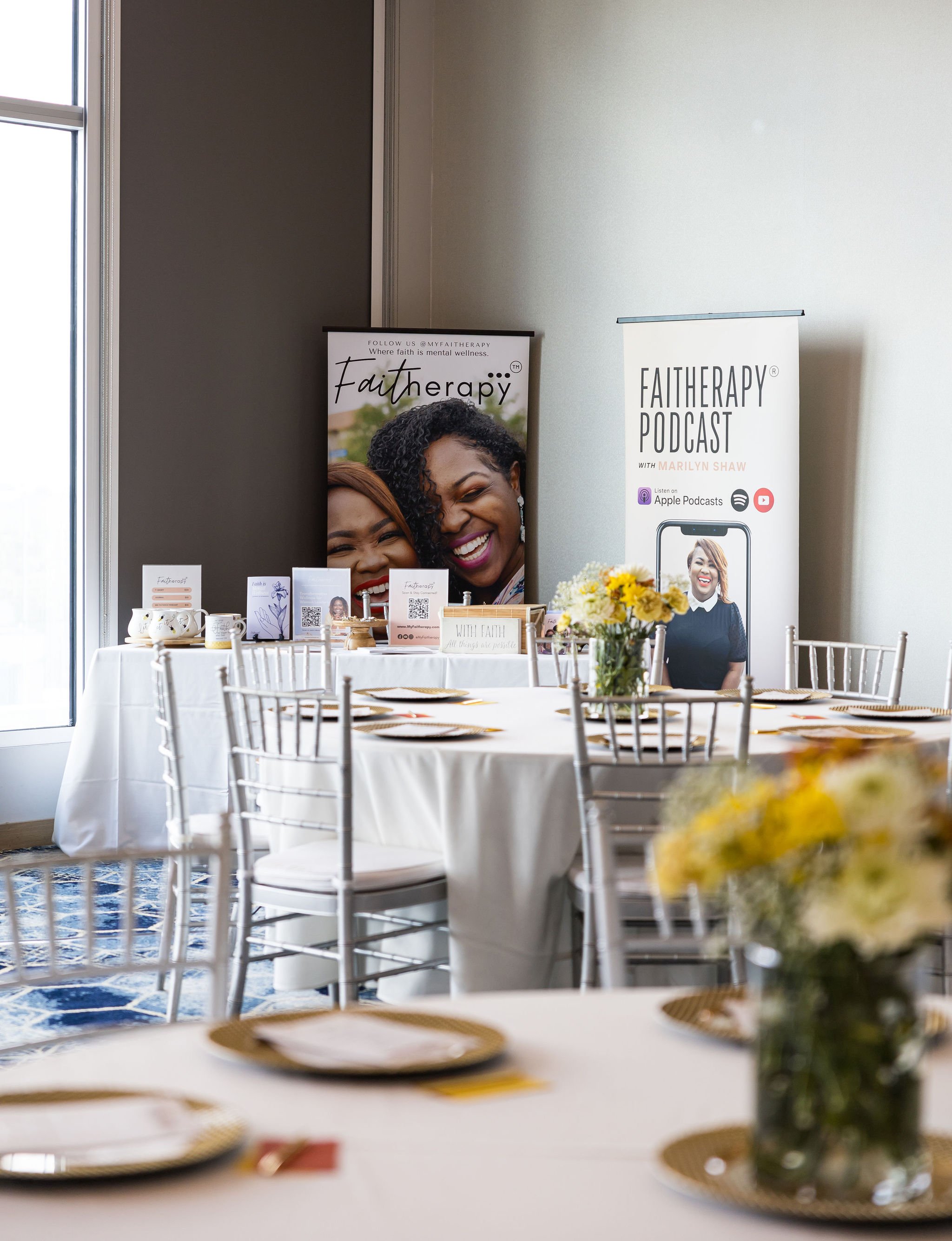Event setup with tables, flowers, and Faitherapy podcast banners