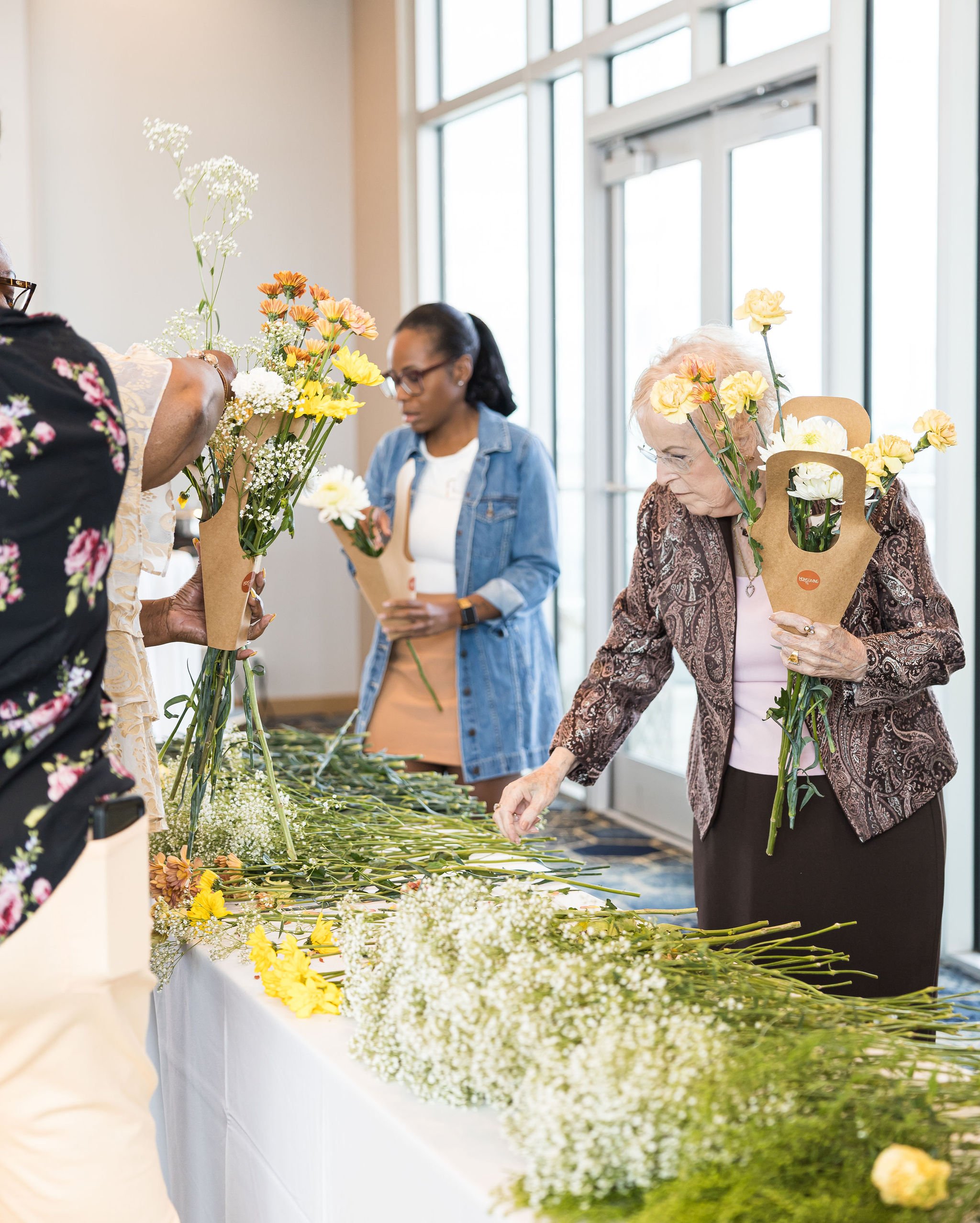 People arranging flowers on a table indoors.