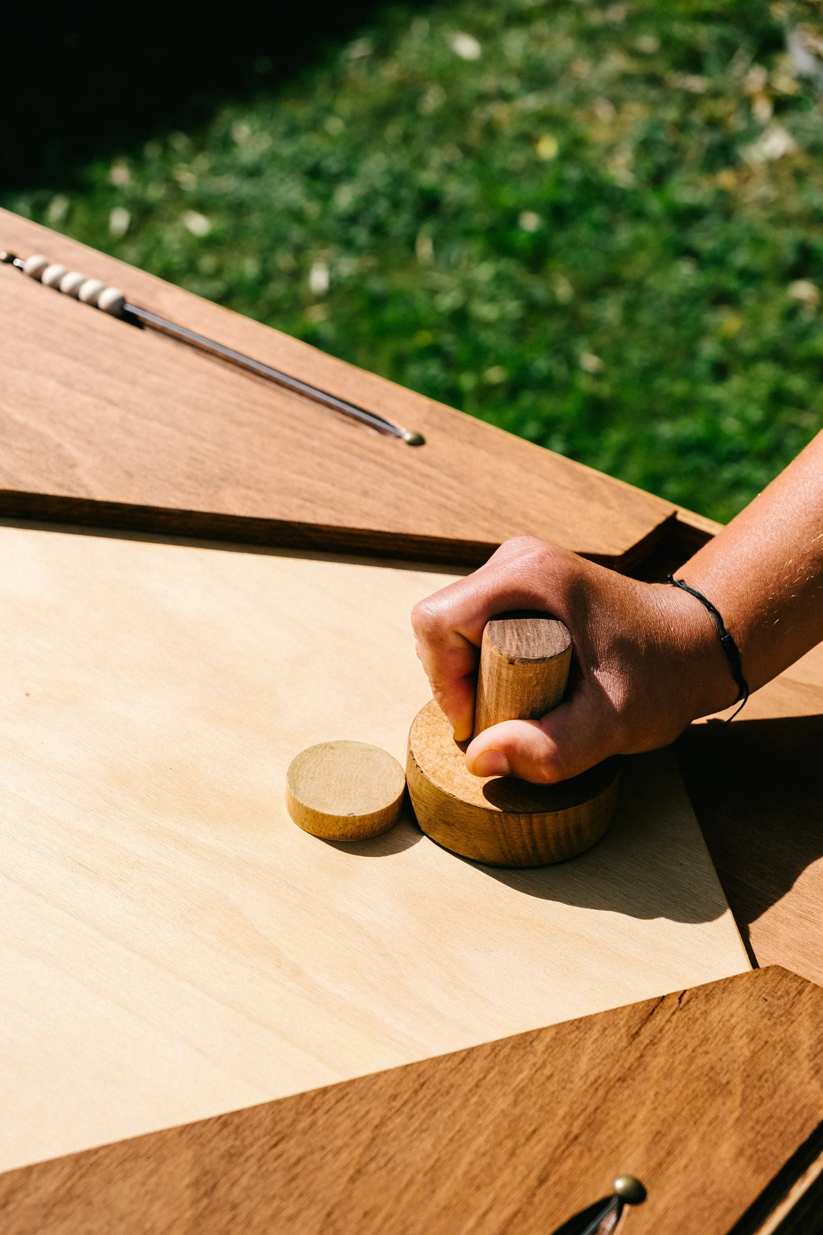 Une personne joue à un jeu en bois avec une table en bois clair et un fond de nature verte.