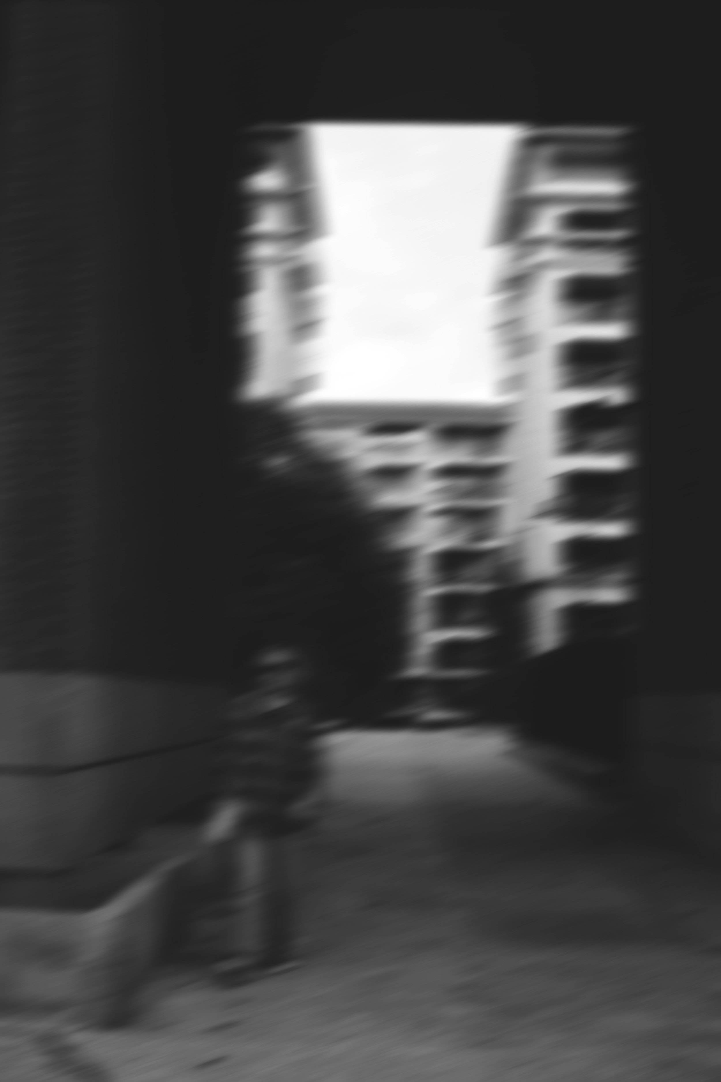 Une pièce sombre avec un grand hublot ou une fenêtre. On voit des bâtiments en dehors et une étagère ou un meuble avec des objets dessus, mais l'image est floue. Editorial