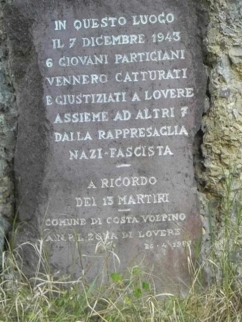 lapide commemorativa con inciso in italiano, dedicata ai giovani partigiani e ai martiri della lotta antifascista del 1943-1945, situata tra erba e piante