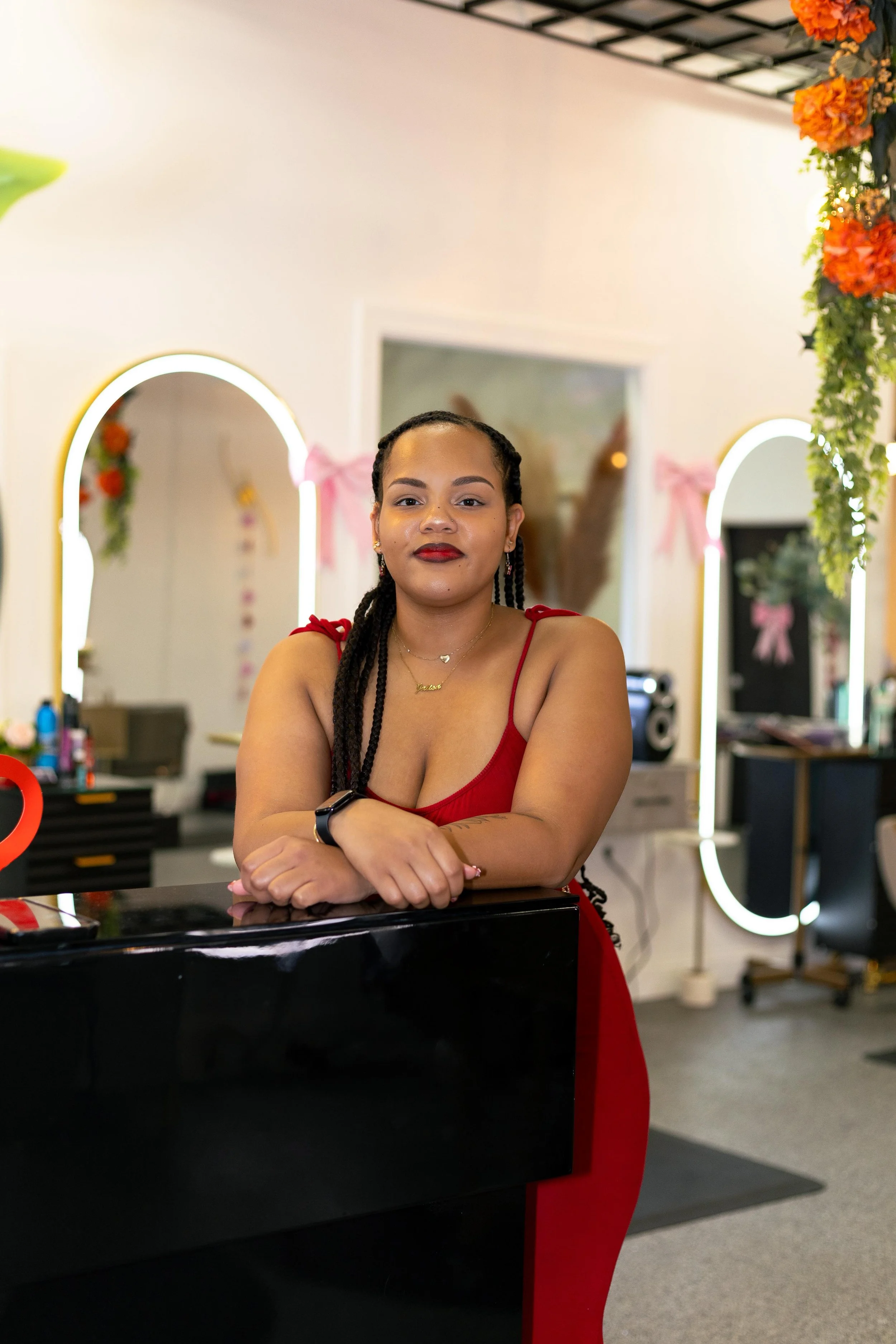 A woman with dark, curly hair smiling, seated indoors in a restaurant or cafe with blurred background of tables and people.