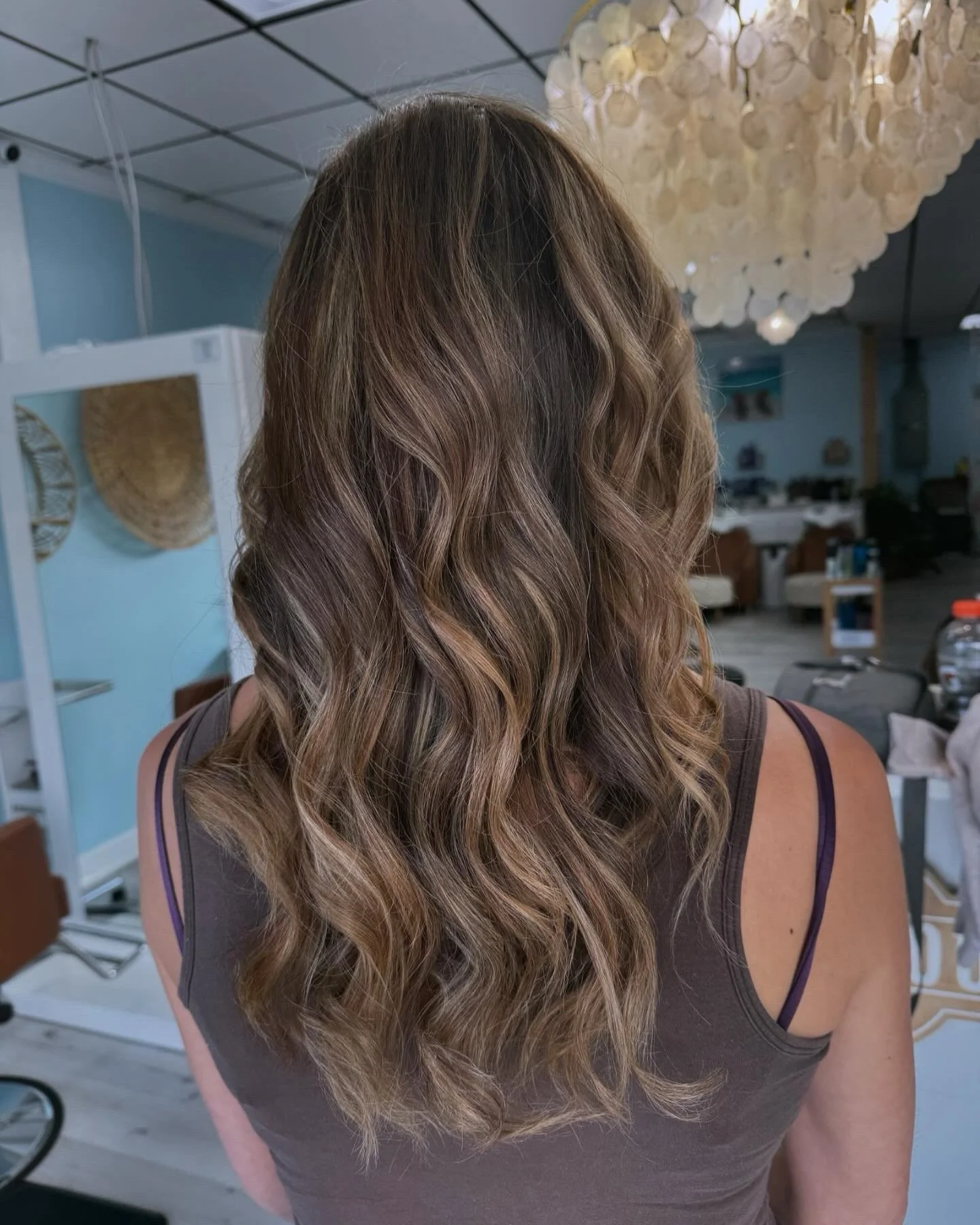 Back of a woman with long, wavy, light brown hair in an indoor setting.