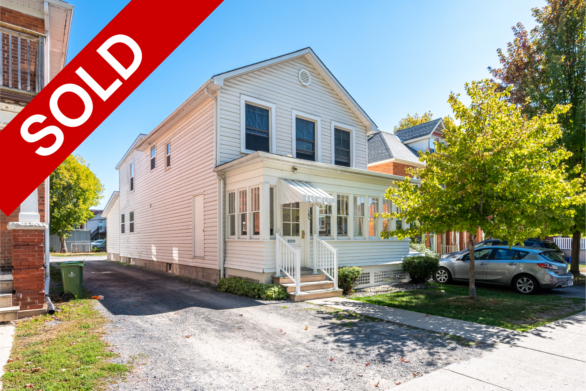 A house with white siding, a small front porch, and a tree in the yard, with a "SOLD" banner overlay.