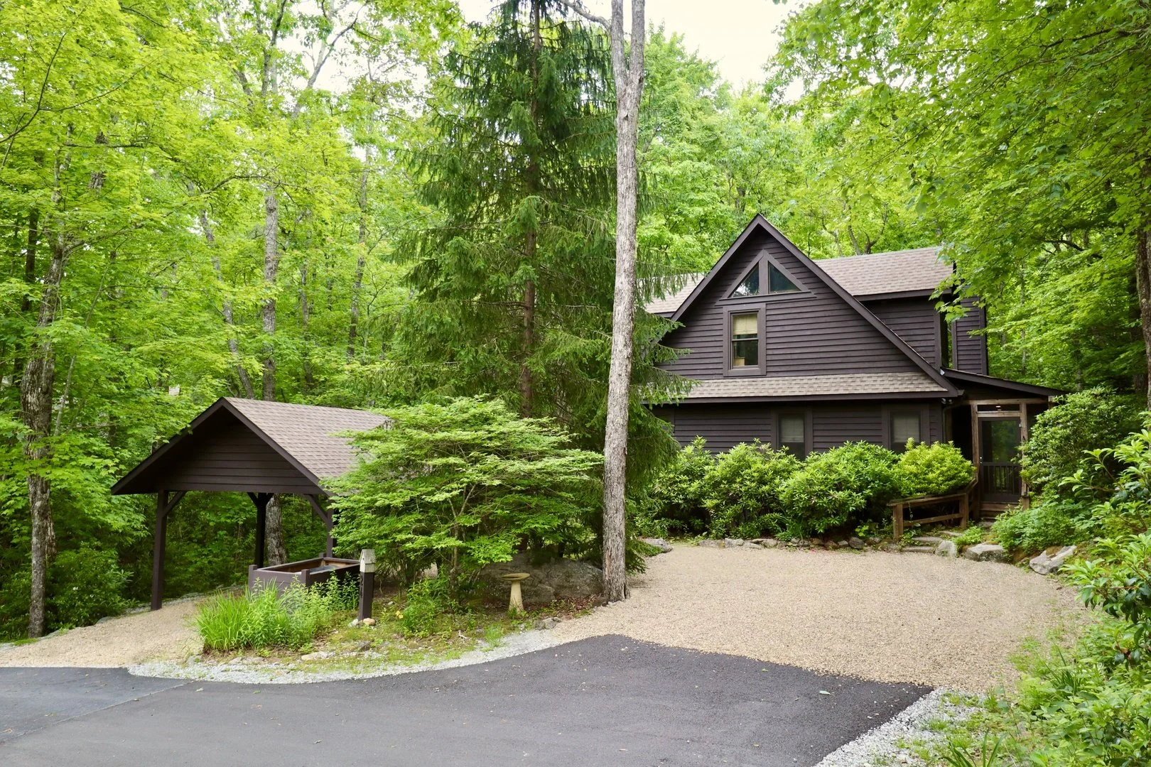 Creekwood Cottage and its covered parking nestled among leafy trees in Highlands, North Carolina.