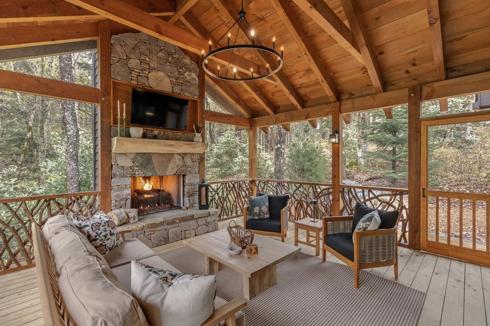 The screened porch at Creekwood Cottage, with comfortable seating and a stone fireplace.