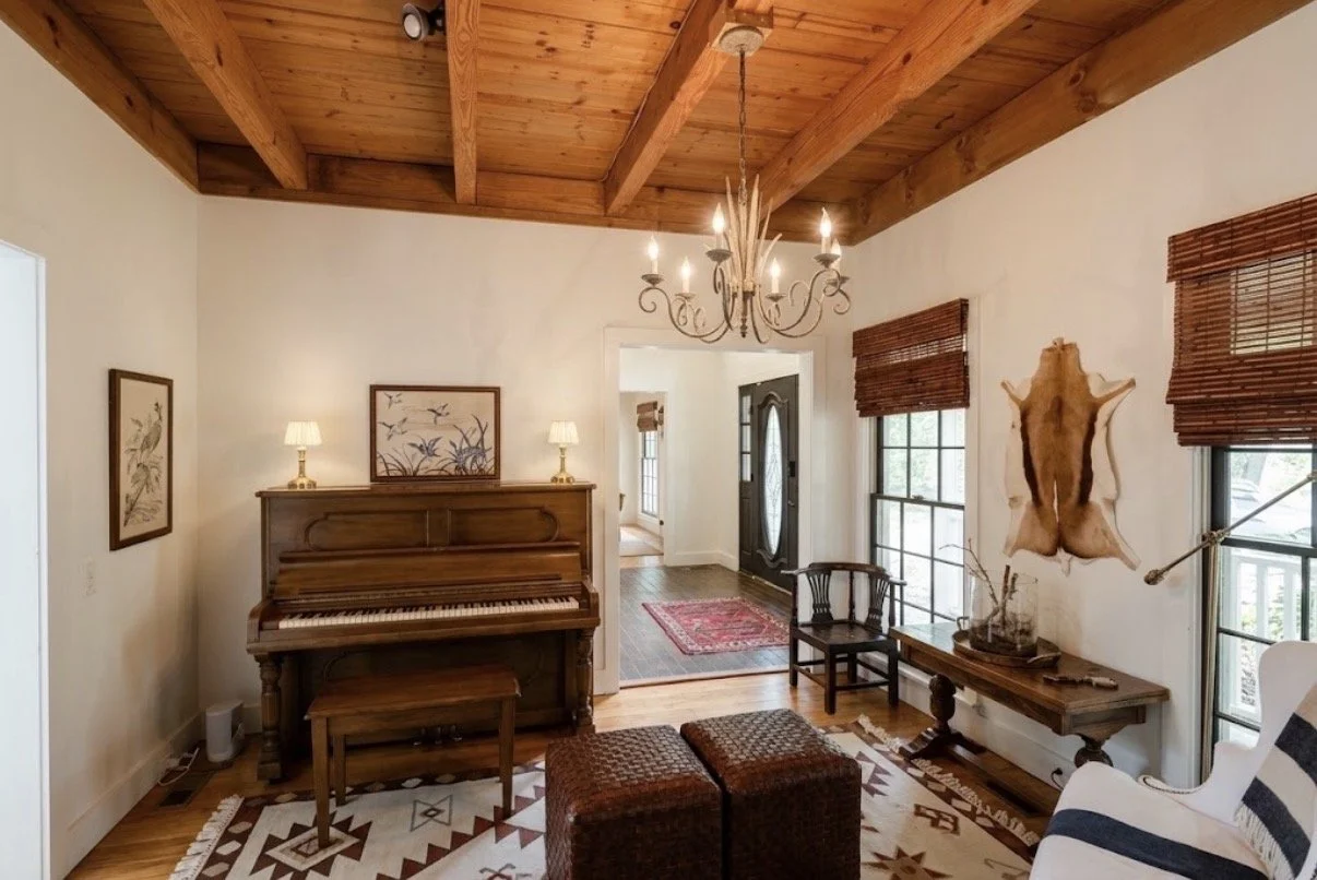 The piano room at Pine Shore Lodge, with timber beams and comfortable seating.
