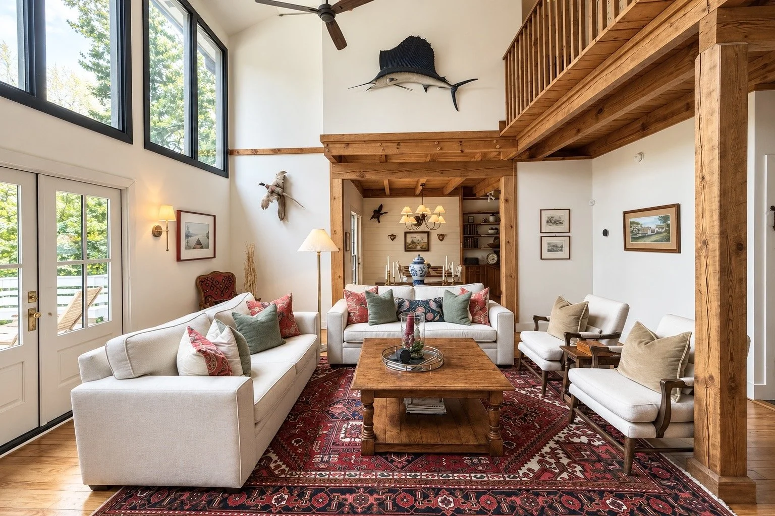 Sunlit living room at Pine Shore Lodge with white sofas, exposed timber beams, and a Persian rug.