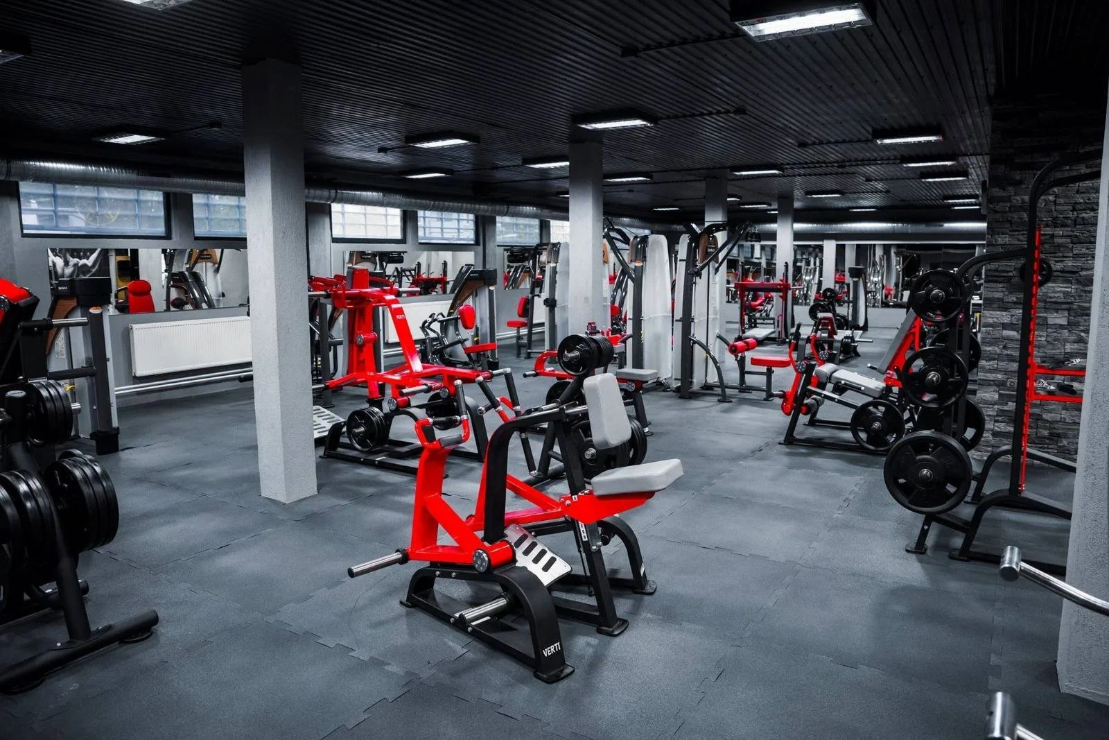Empty gym with weightlifting equipment, benches, and weights in a modern fitness center.