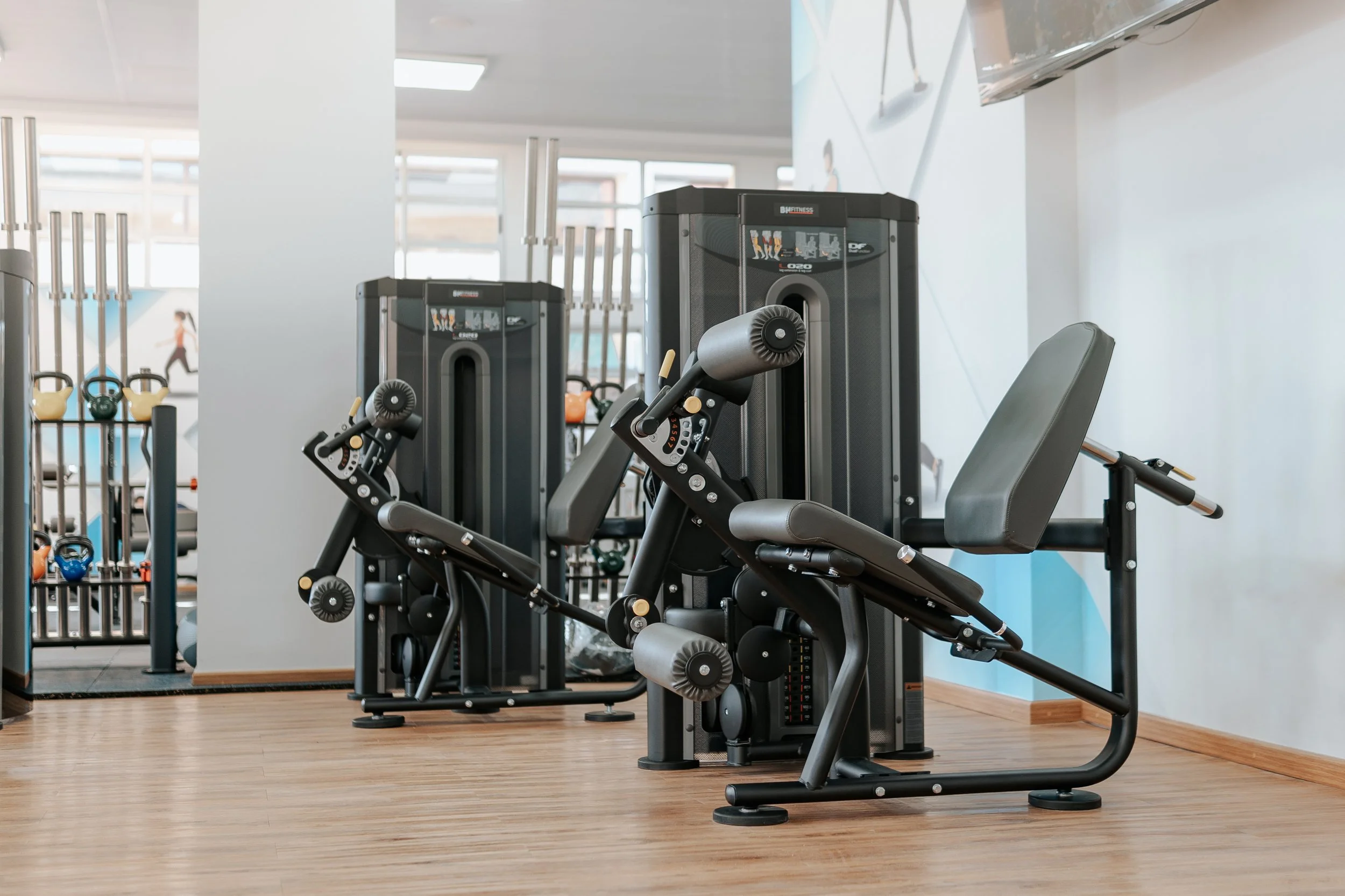 Gym equipment including a leg extension machine and a seated leg curl machine in a fitness center.