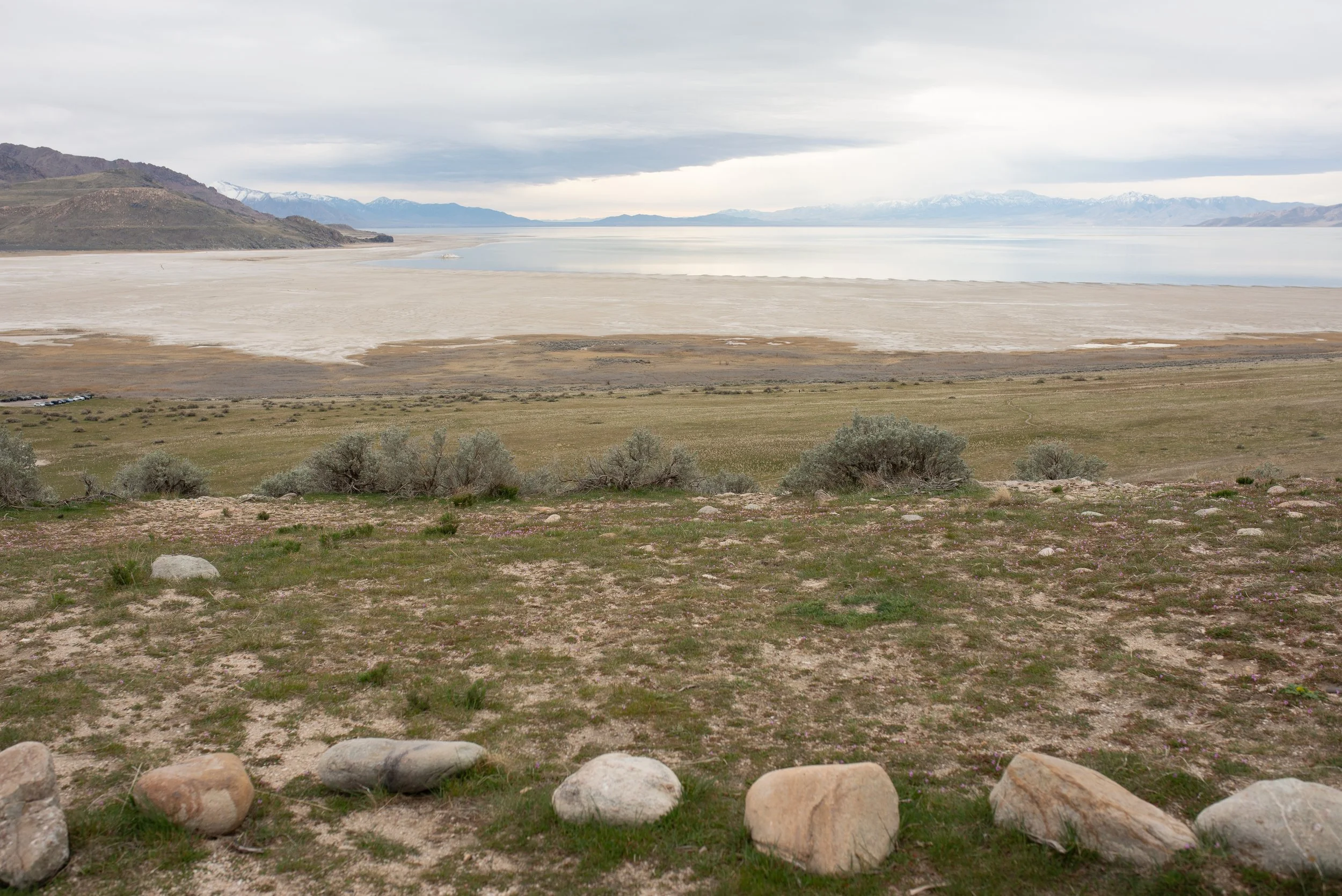 Overlook of Great Salt Lake from Antelope Island with rocky foreground and distant mountains under cloudy sky