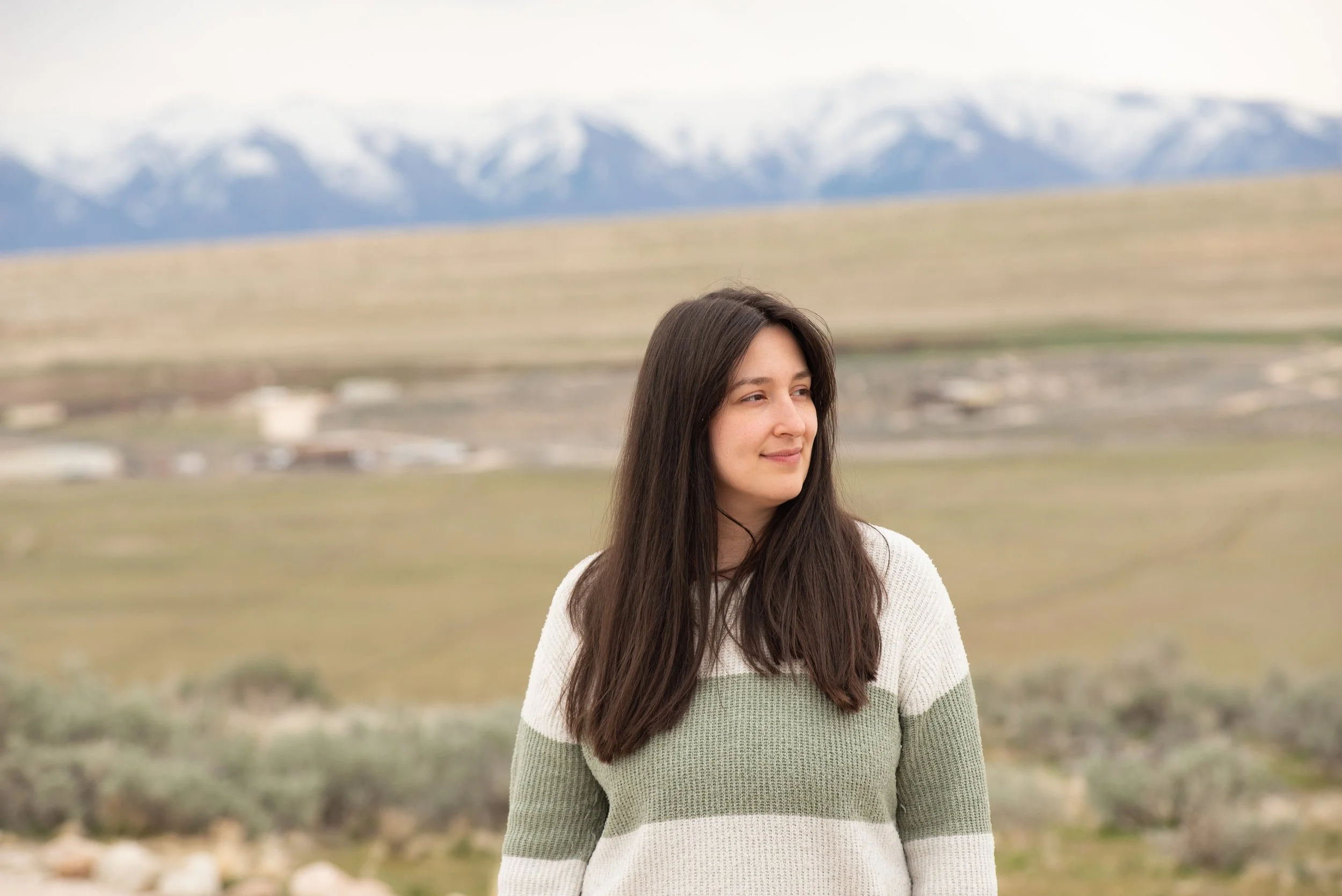 Woman standing on Antelope Island with blurred snowy Wasatch Mountains in background