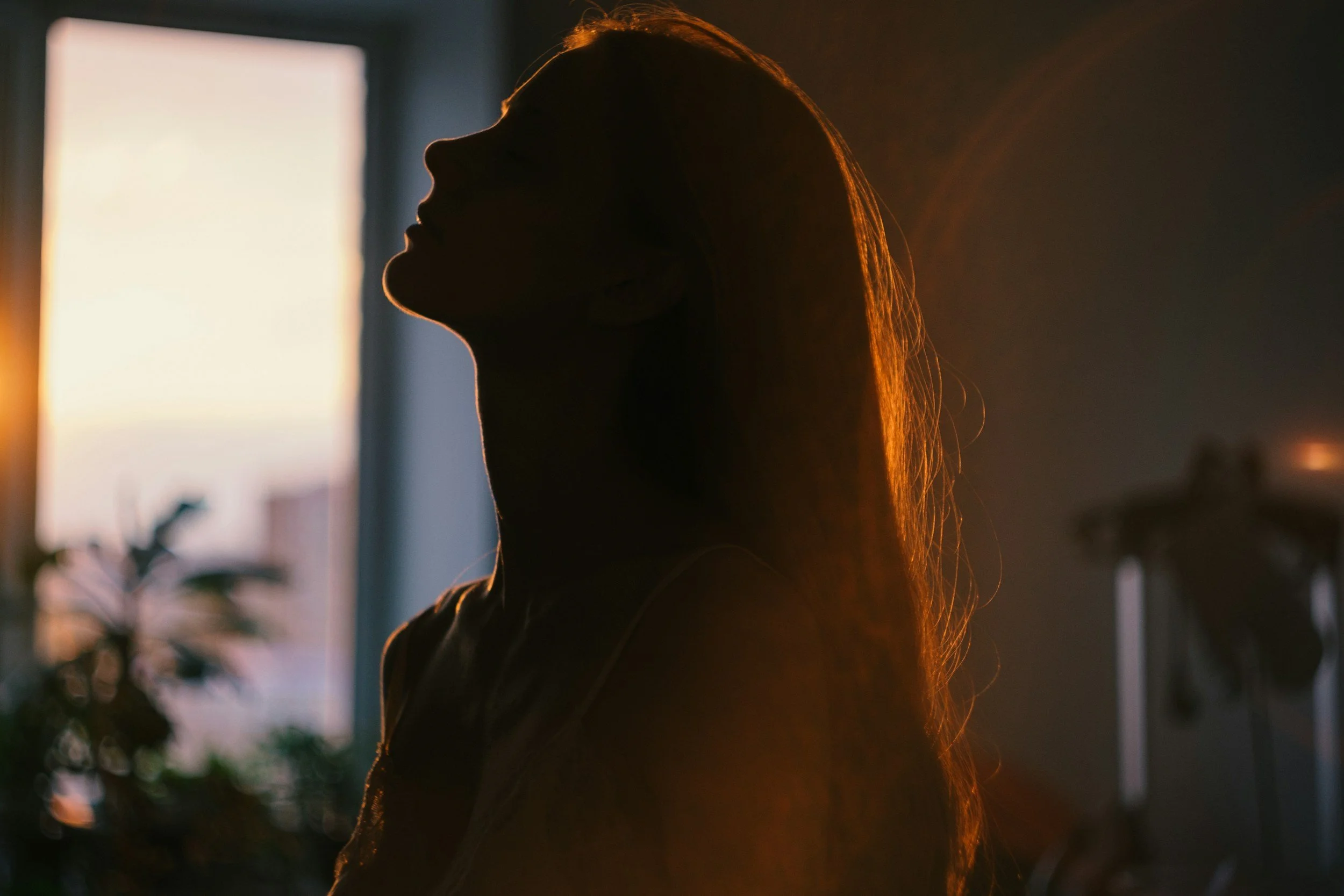 Woman reflecting by a window, representing therapy for women's mental health