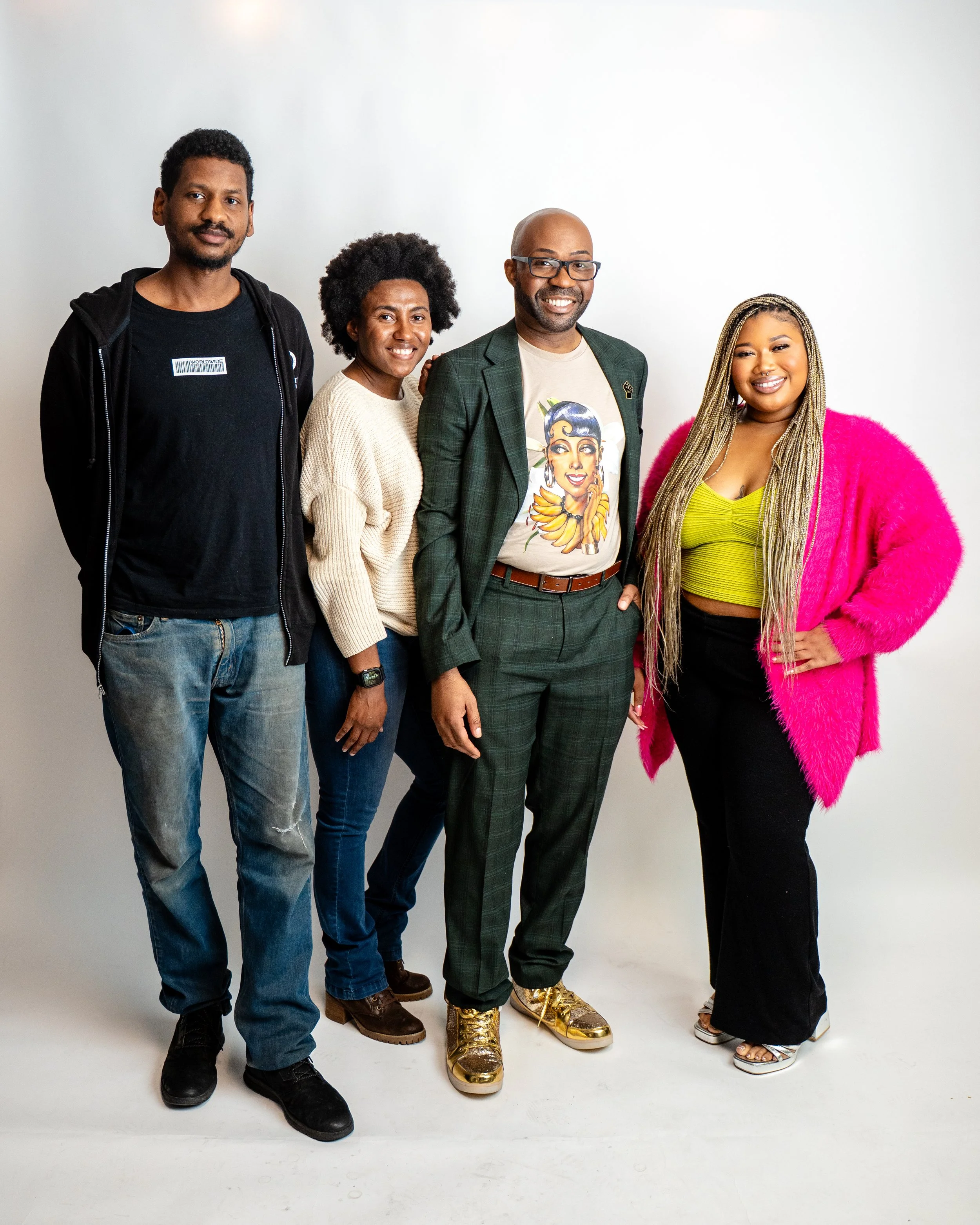 Group of five diverse people standing together against a white background, smiling and posing for the camera.