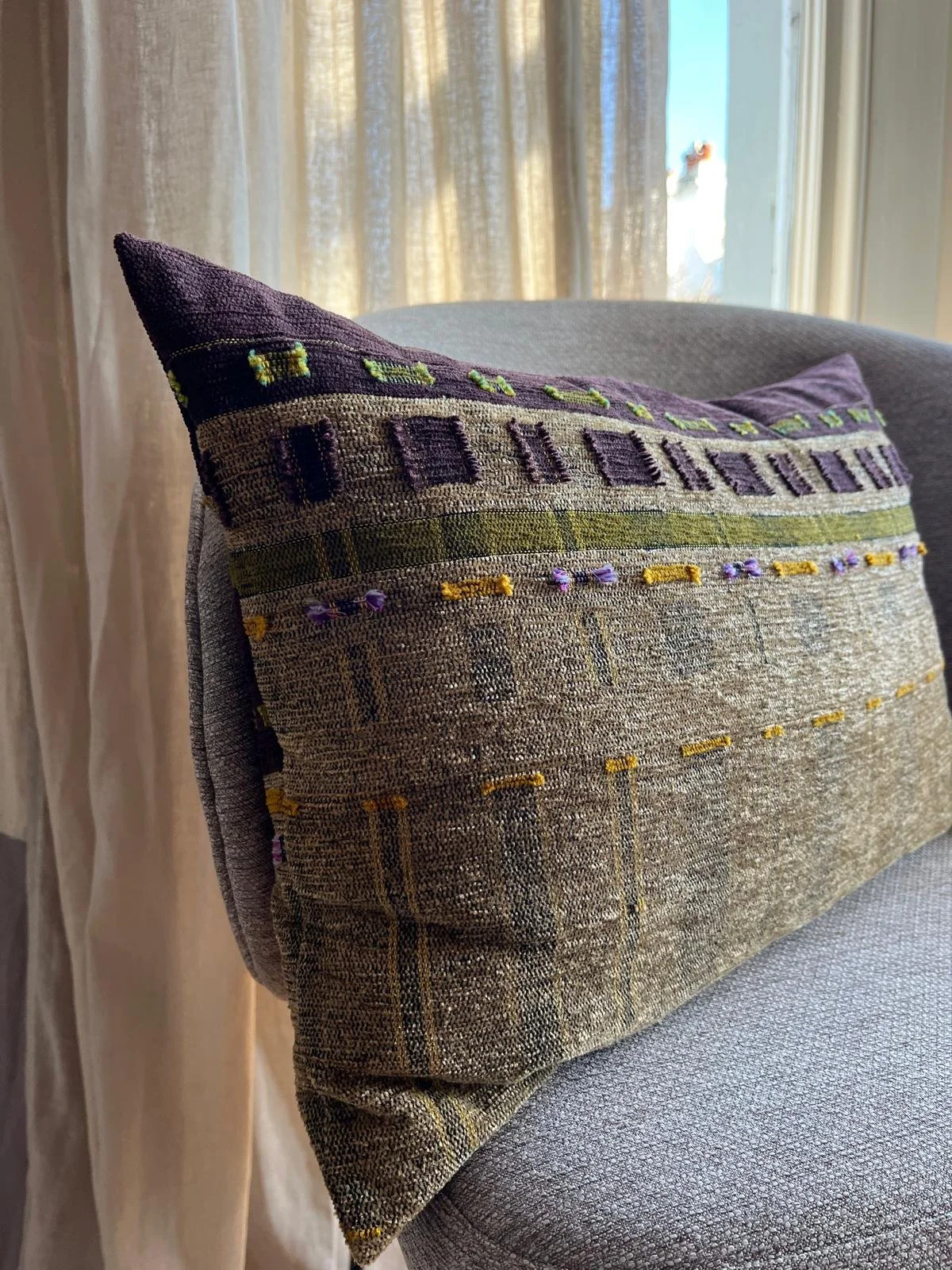 Handmade cushion on bedroom accent  chair with sheer curtains behind.