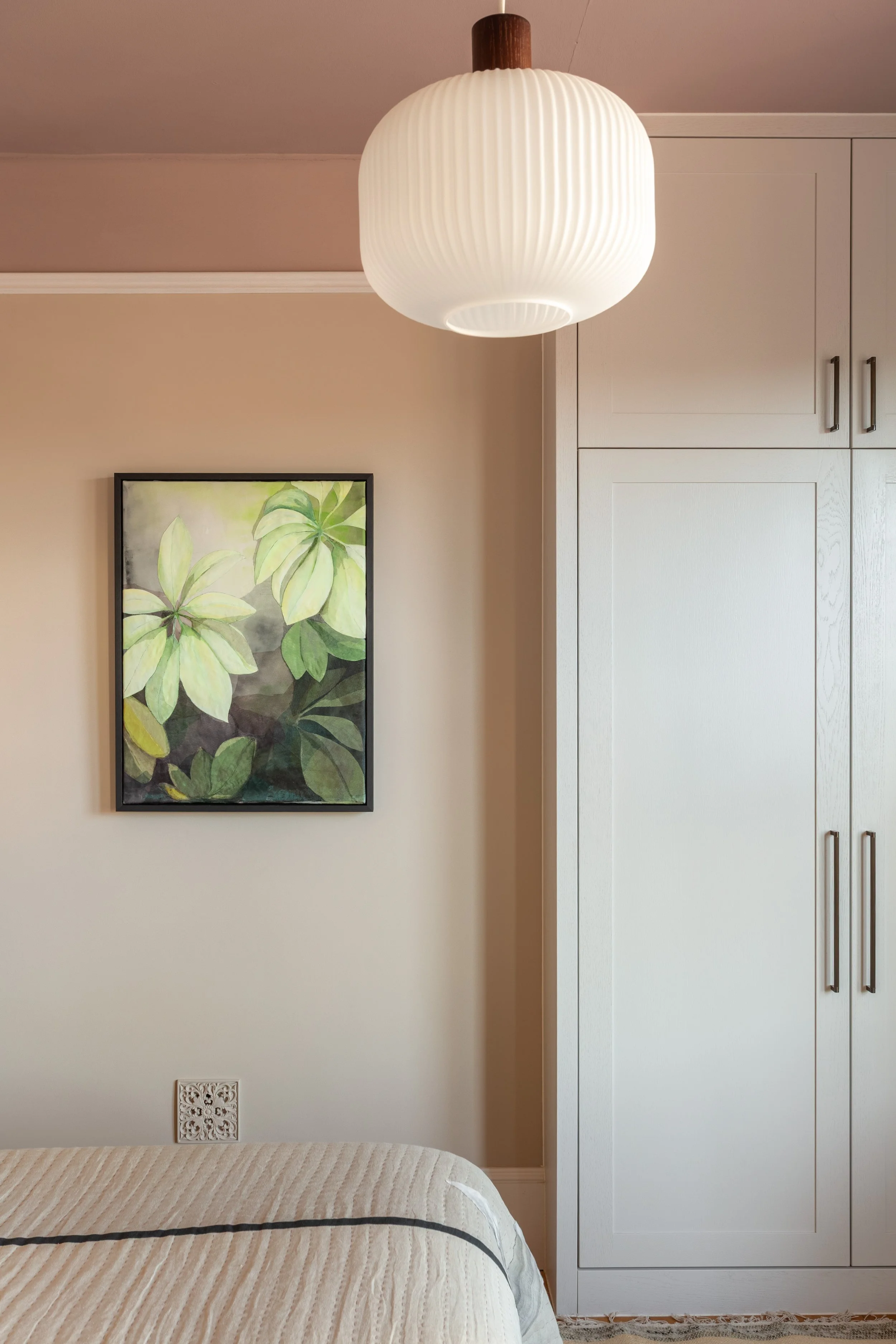 Elegant bedroom with warm neutral colour palette, bespoke built in wardrobe, bespoke textile framed artwork and wooden flooring.