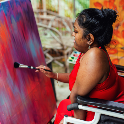 Person in a wheelchair painting on a canvas with vibrant colors