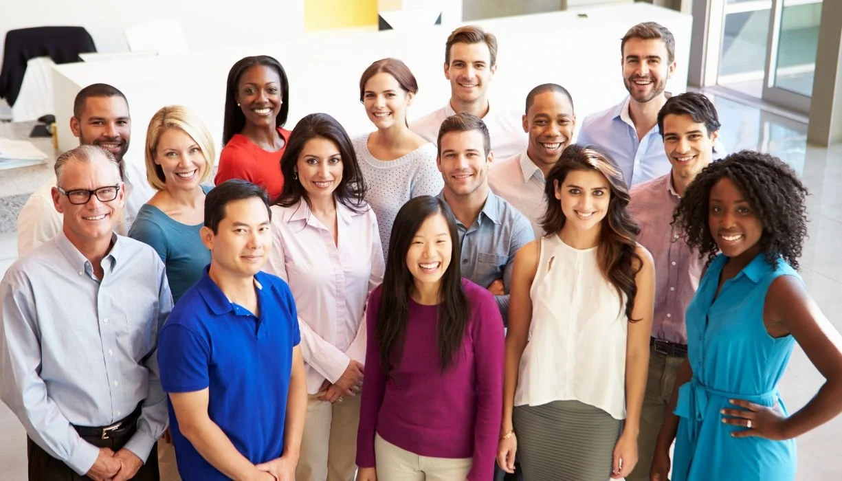 Group of employees smile at the camera wearing business casual clothing.