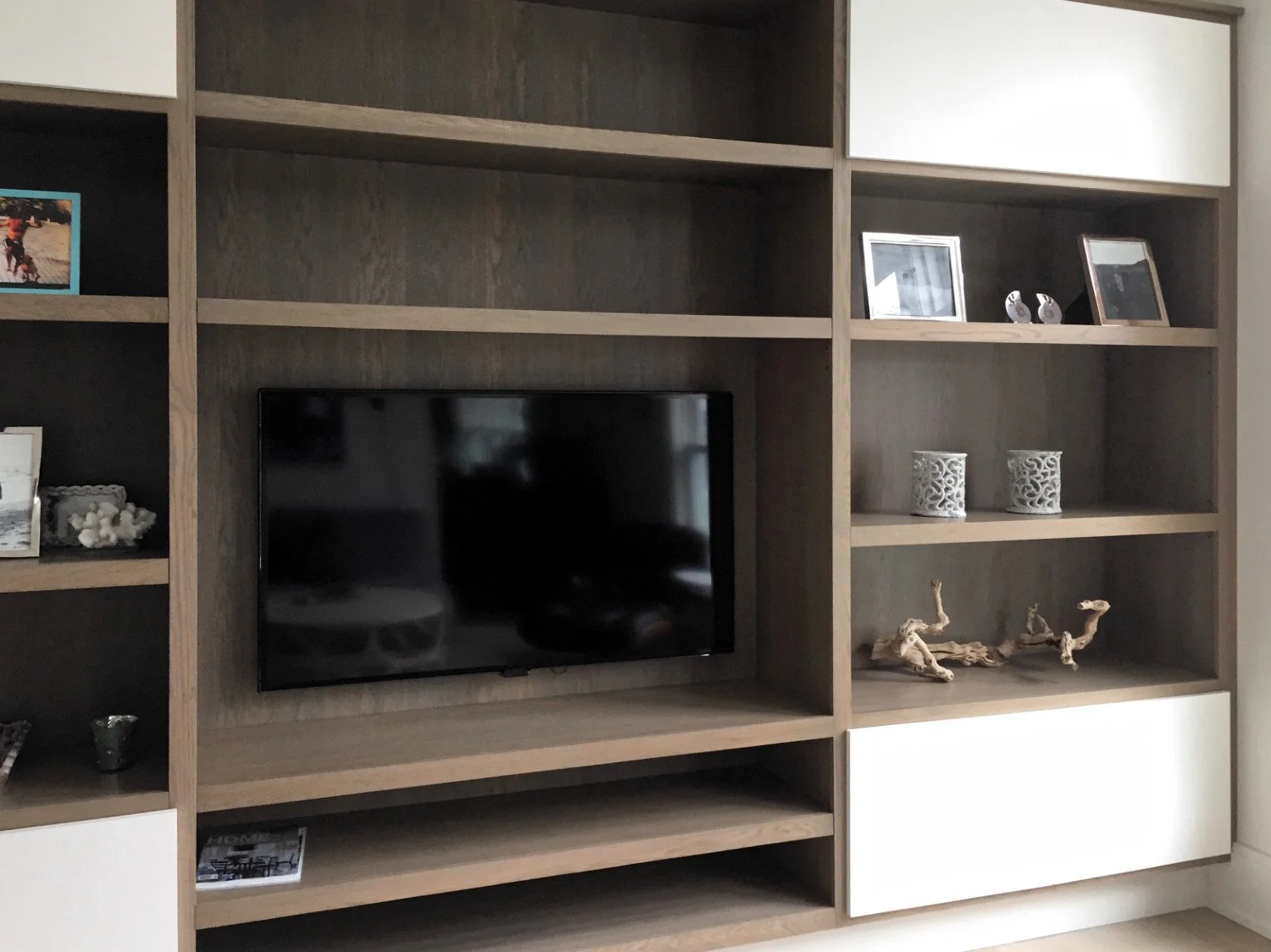 Living room entertainment center with a mounted TV and decorative items.