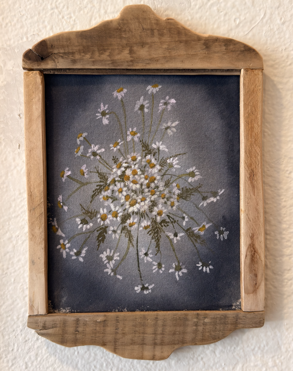 A framed painting of a bouquet of small white daisies with yellow centers, with a butterfly on the right side, set against a dark background.