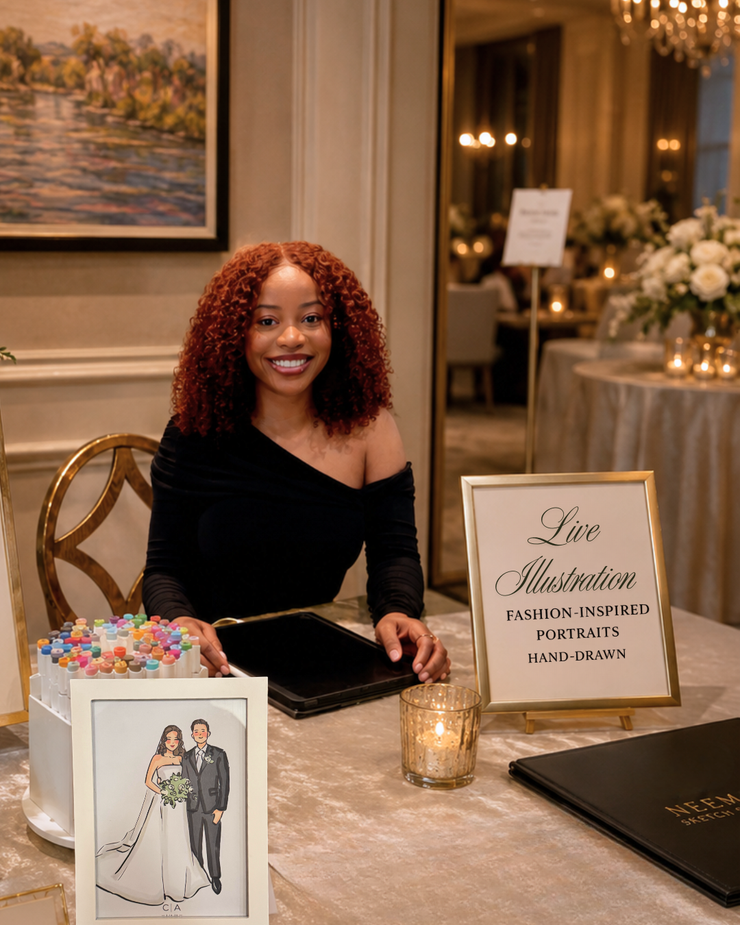 Neema sitting at her live event illustration station with markers and custom wedding portraits.