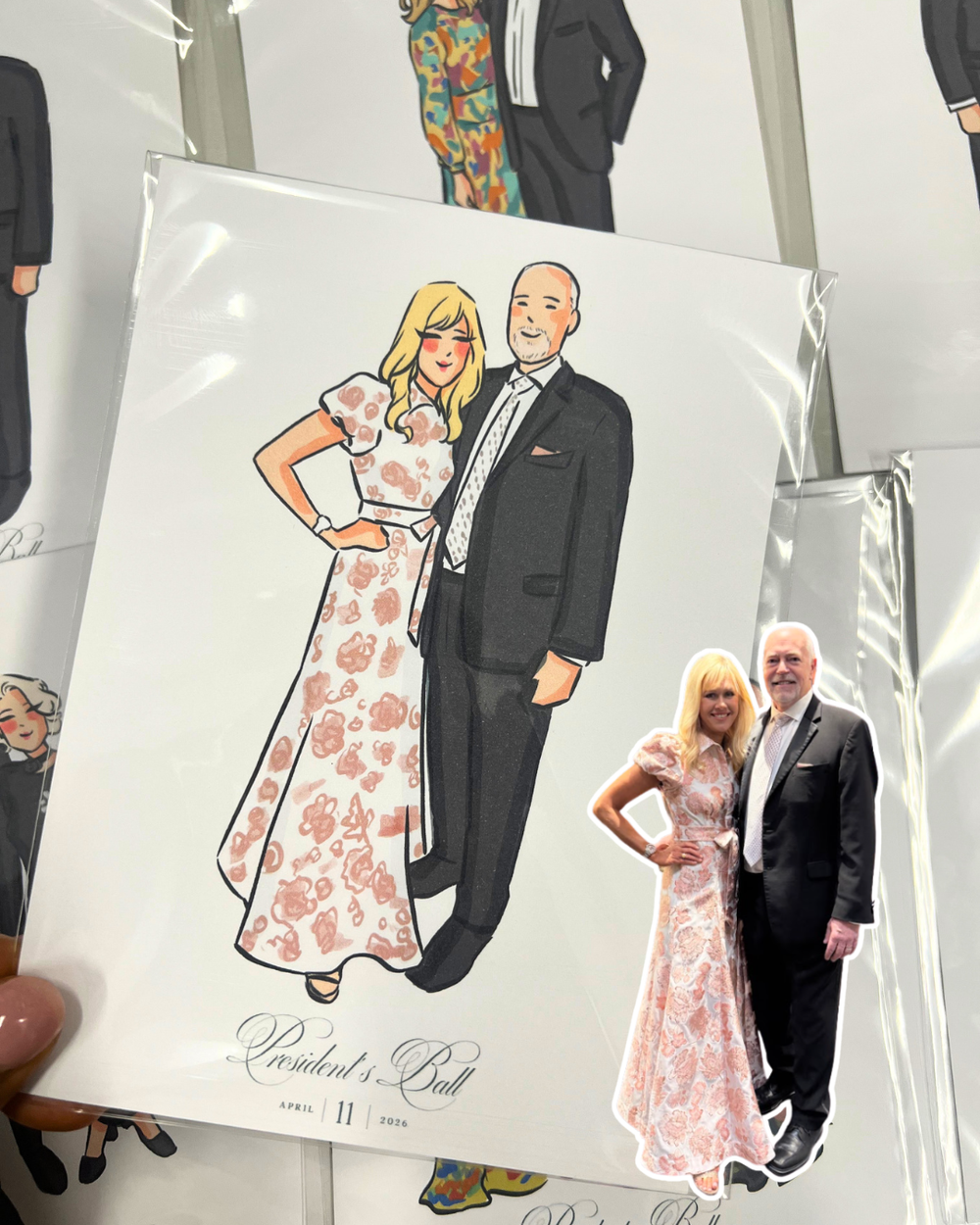 A pressed souvenir photo features a woman in a pink floral dress standing next to a man in a black suit. The image includes a cartoon illustration of the same couple, with the woman in a pink dress and the man in a black suit, along with the text 'Pr