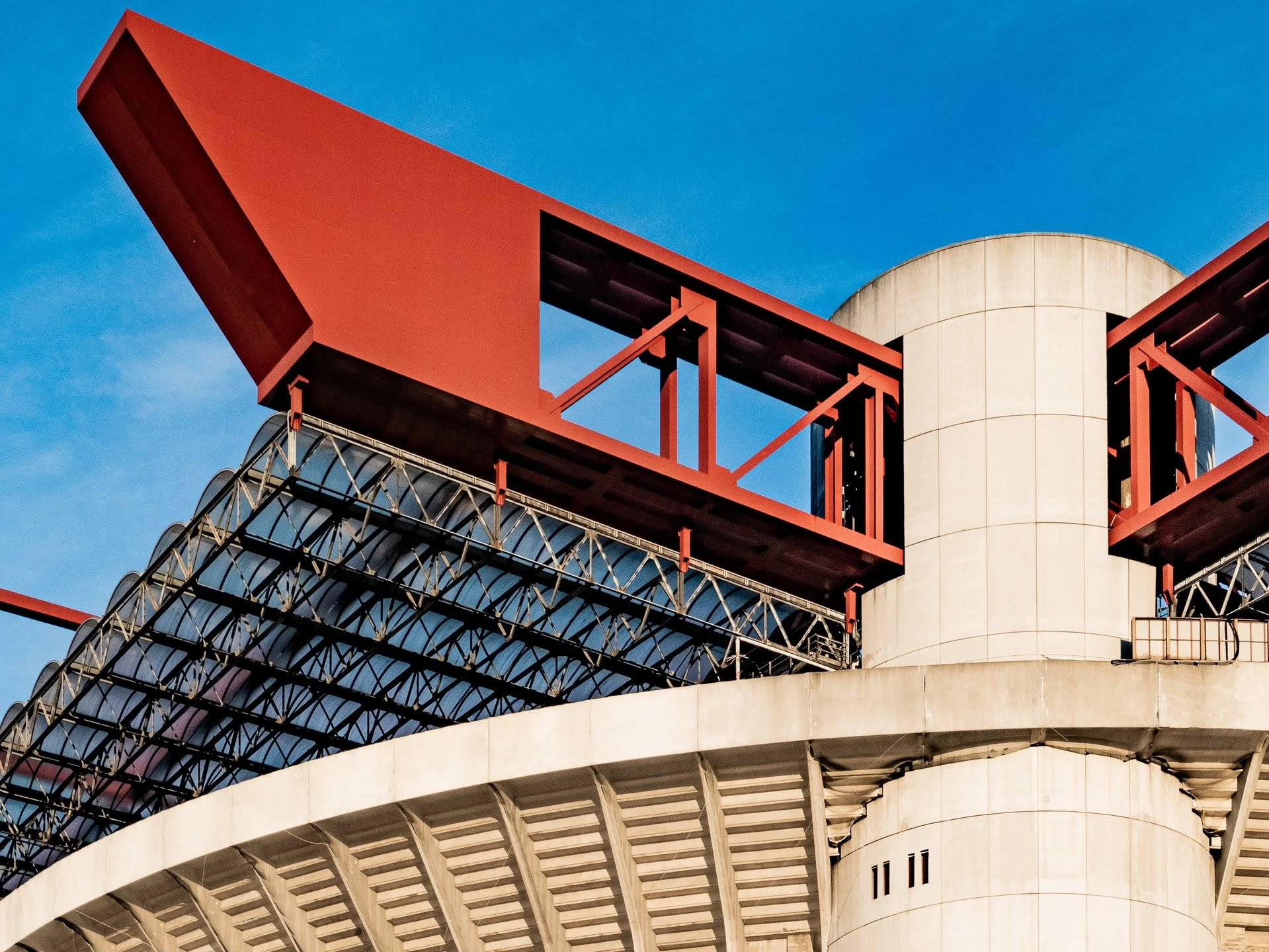 Structure above the spectacle.

A recent visit to Milan revealed another layer of San Siro&rsquo;s architecture as red crowns the stadium and frame its immense scale.

Suspended above the exposed concrete below, the trusses introduce colour, rhythm, 
