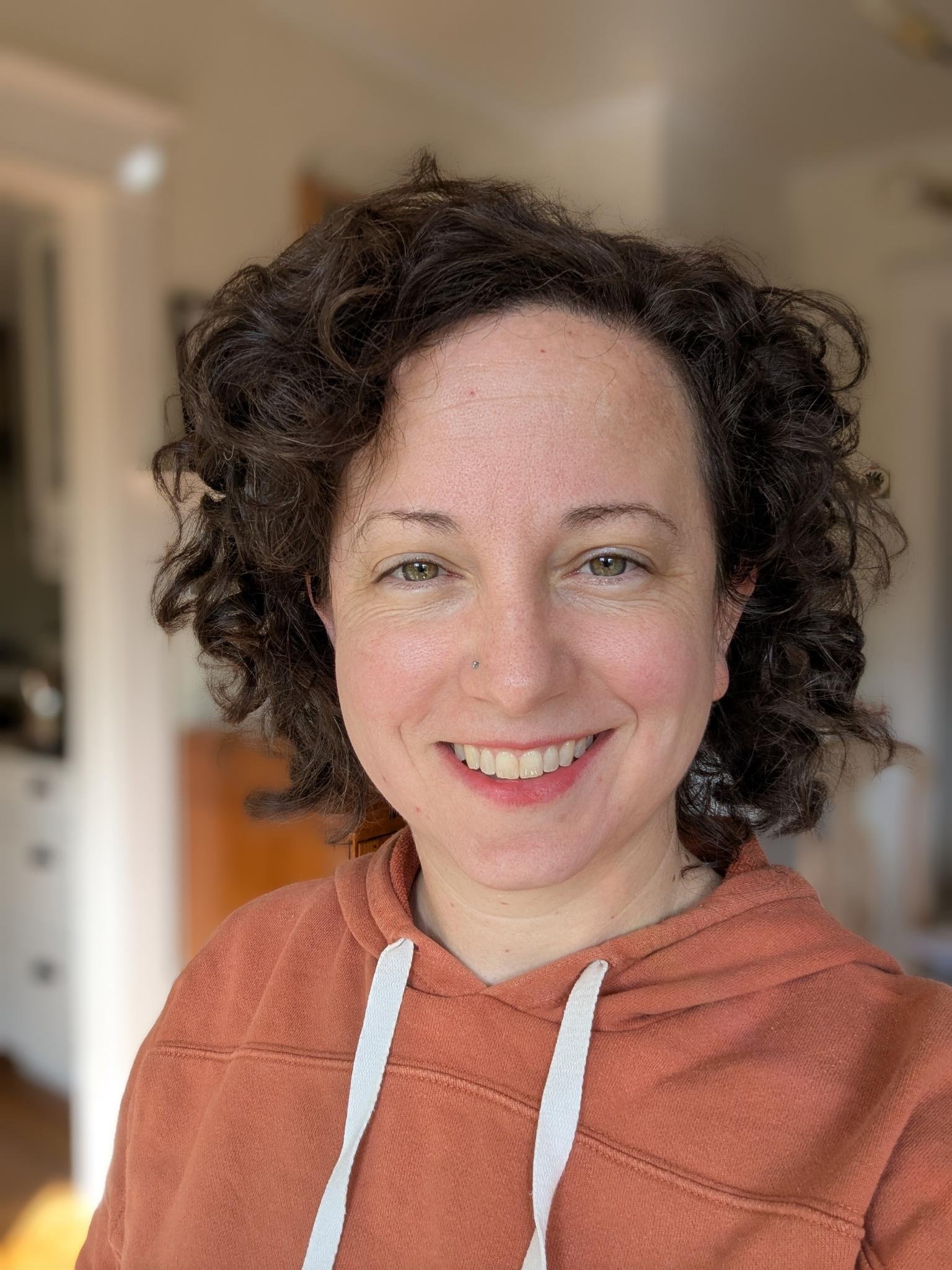 A picture of a woman smiling with curly hair