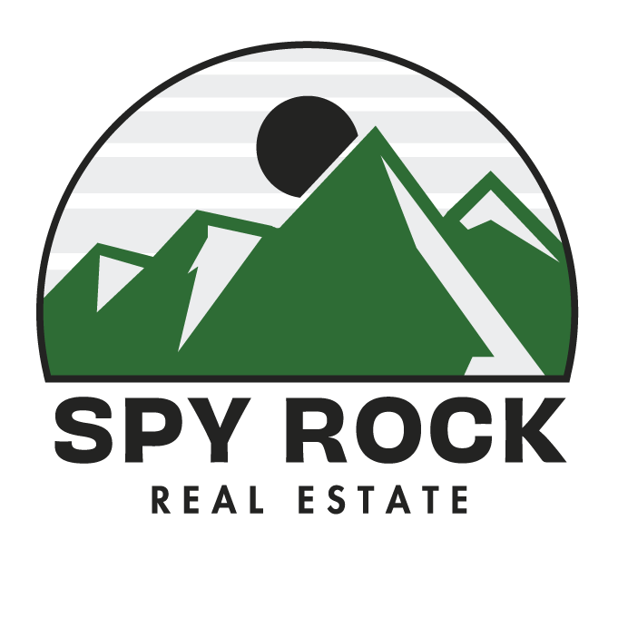 A circular logo with green mountains, a black sun or moon, and the text 'SPY ROCK REAL ESTATE' beneath the mountains.