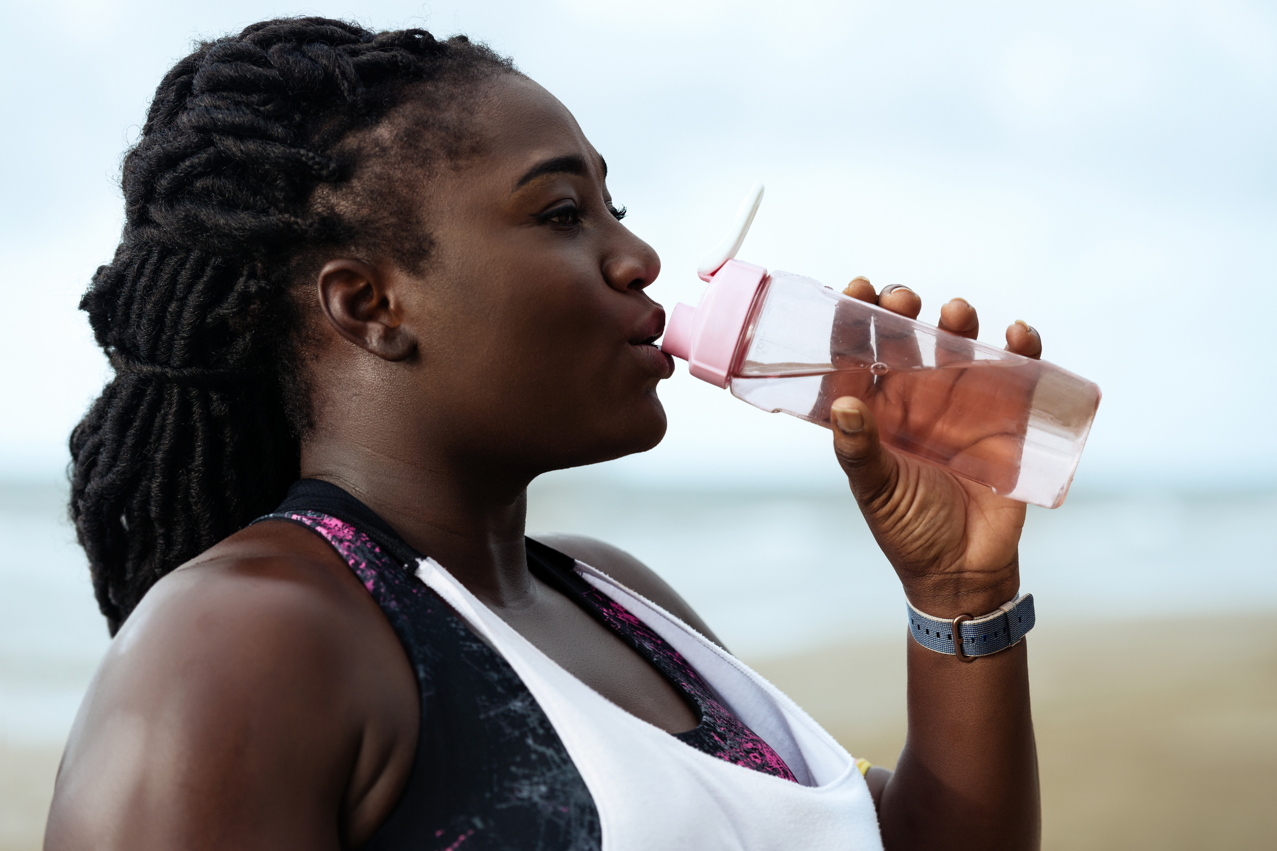 Woman in white tank top drinking water from a bottle