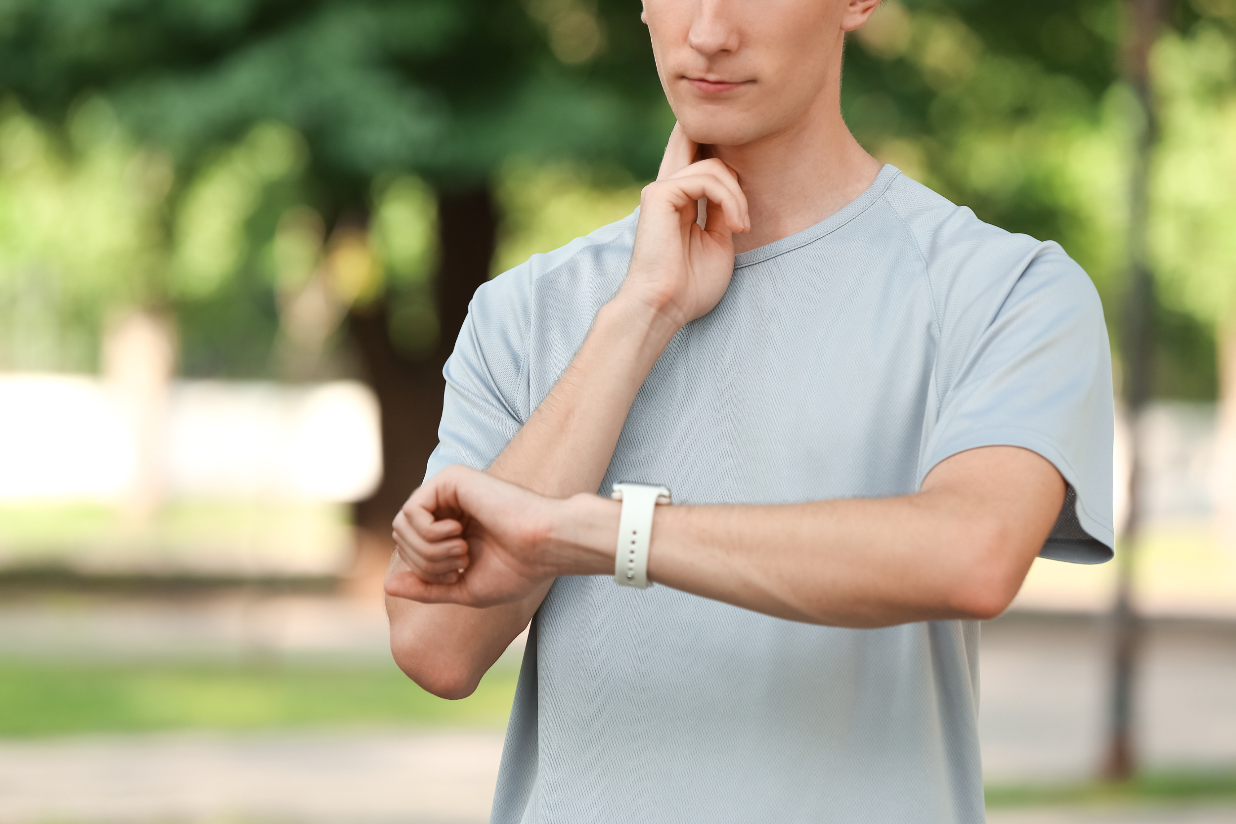 Man in grey t-shirt checking his pulse on his neck and smartwatch for heart rate
